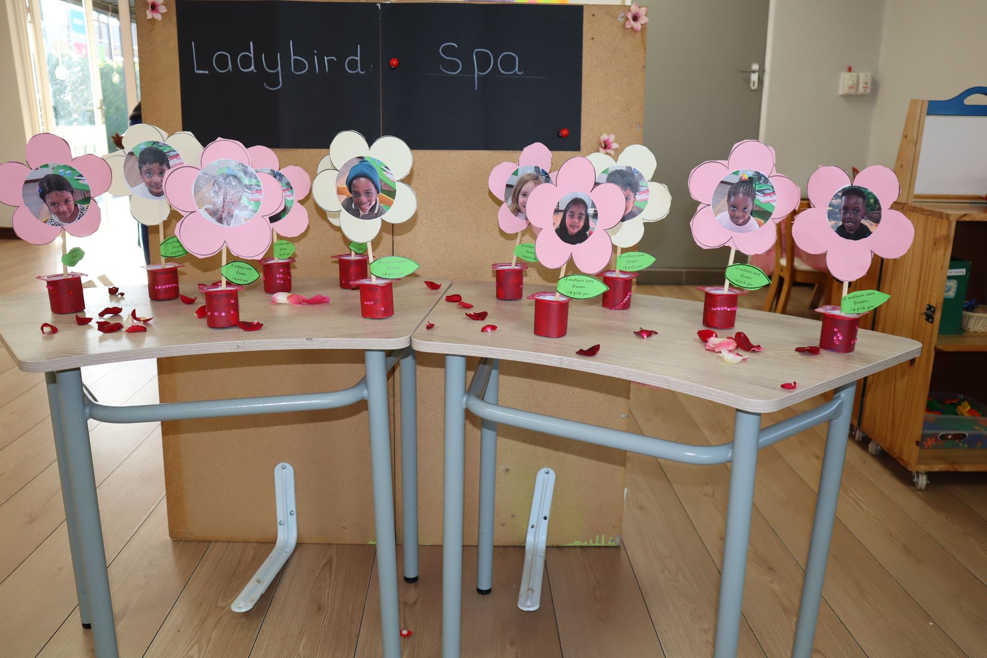Pink flower crafts with children's photos on two tables, 