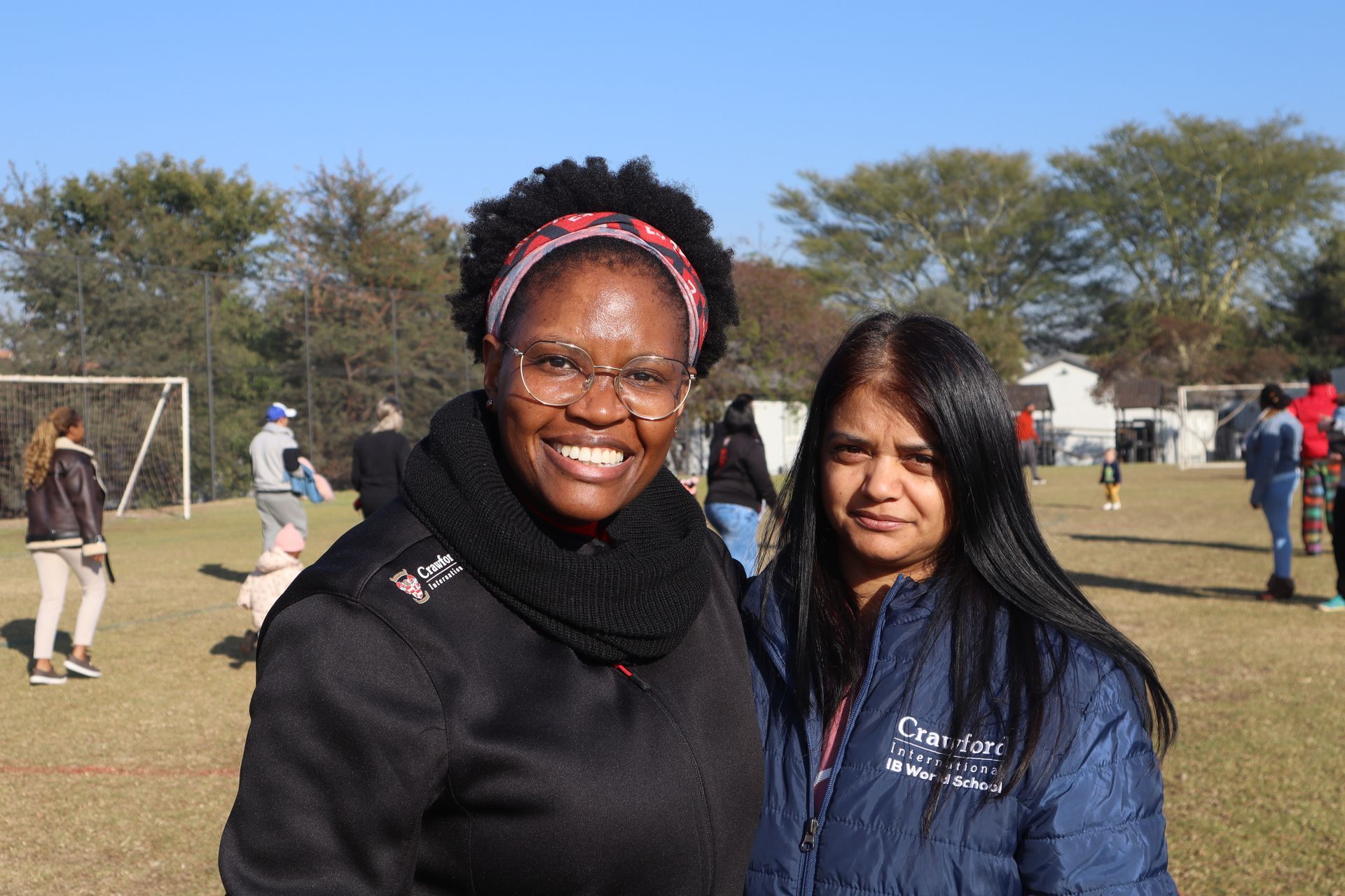 Two women are posing for a picture in a field.