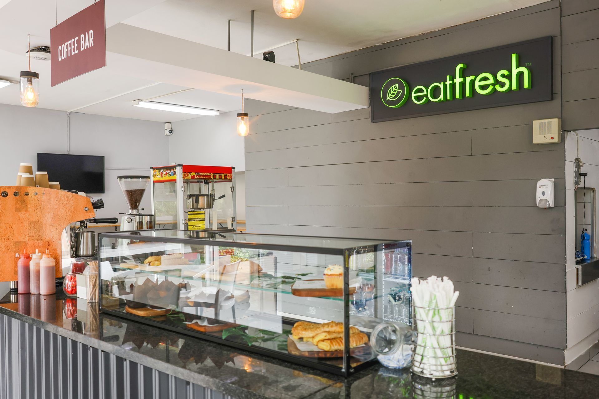 a restaurant with a long counter and coffee bar along with pies