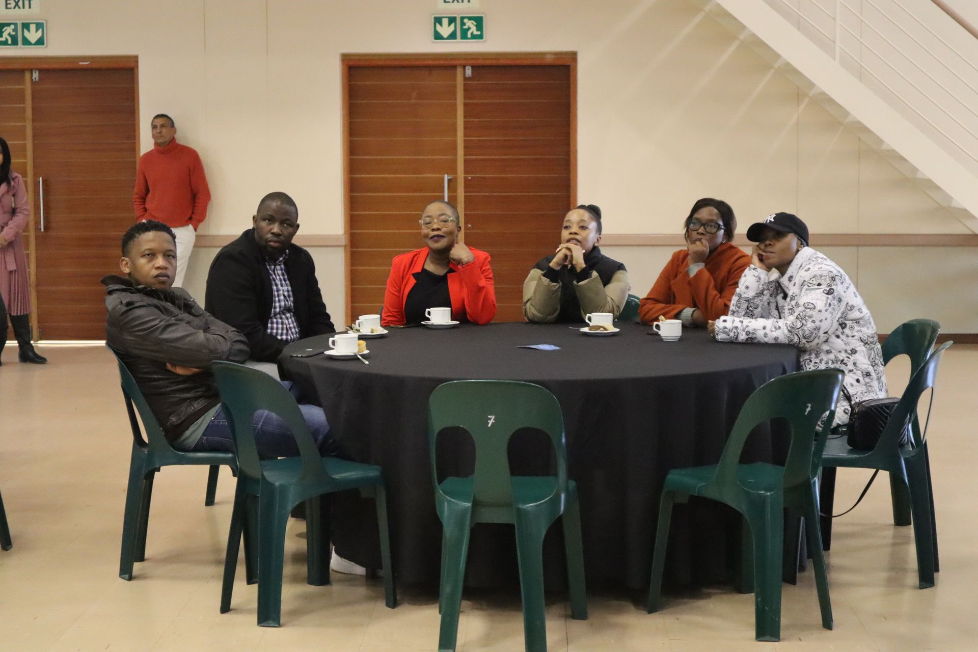 A group of people are sitting around a table with cups of coffee.