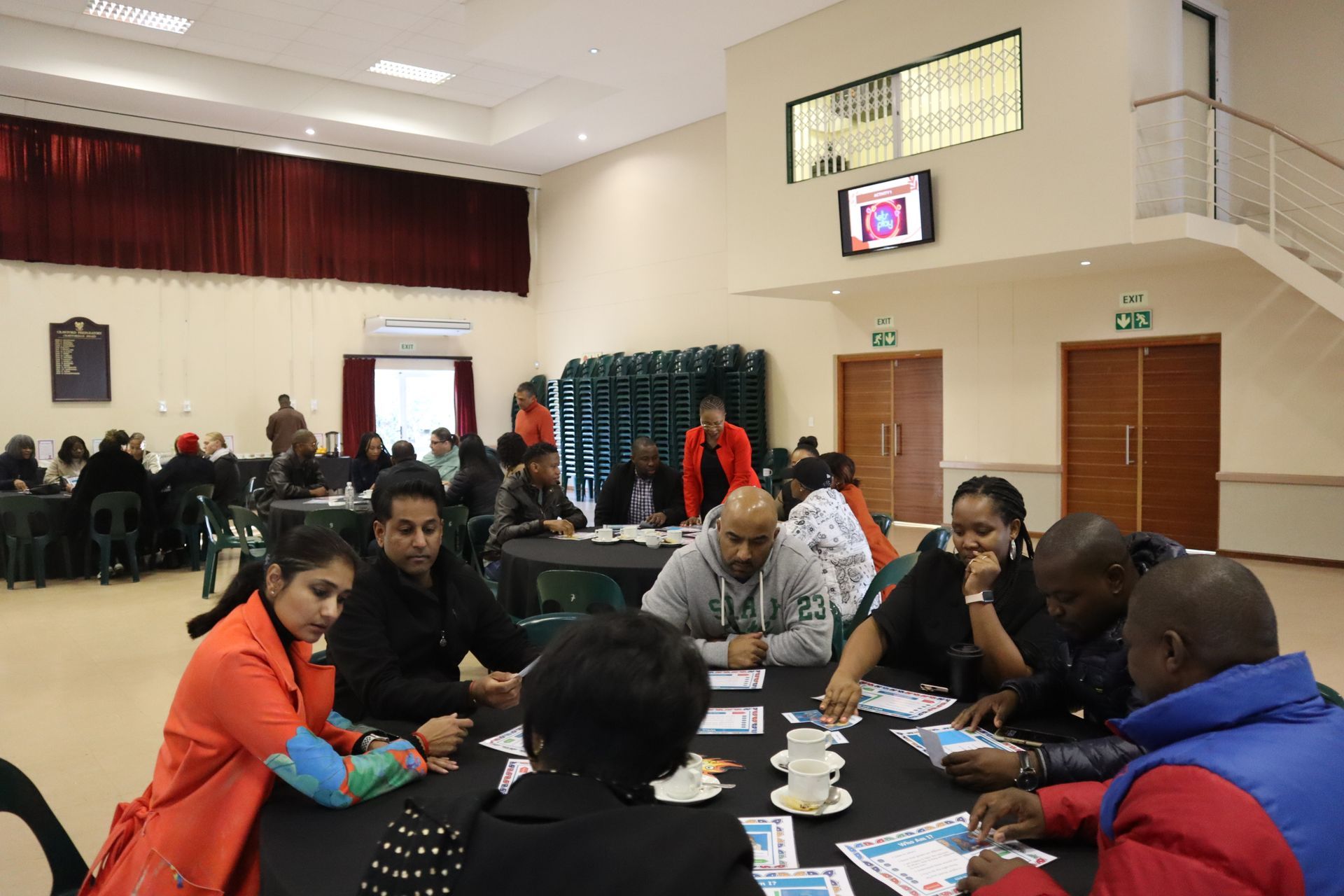 A group of people are sitting around a table in a large room.