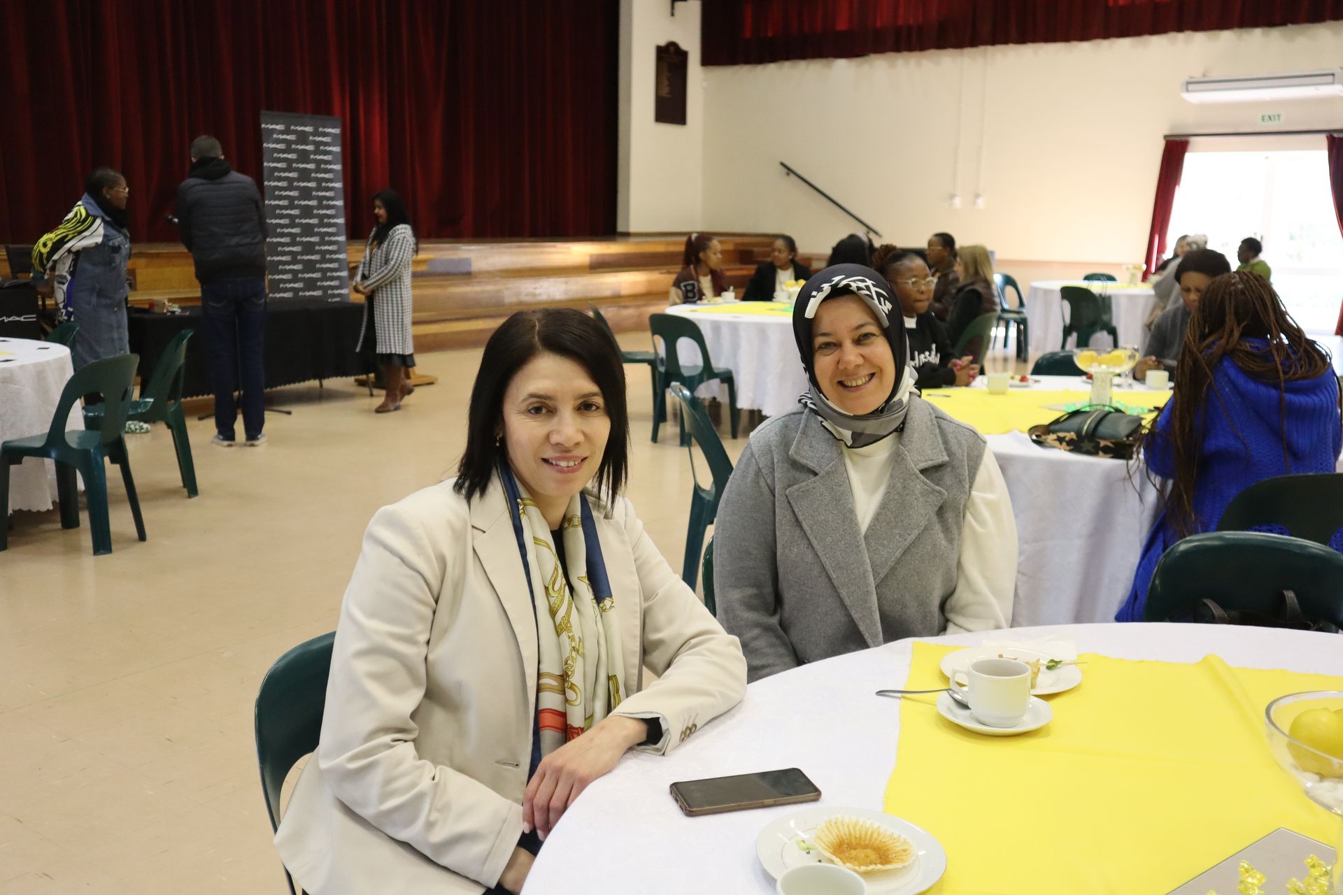 Two women are sitting at a table in a room.