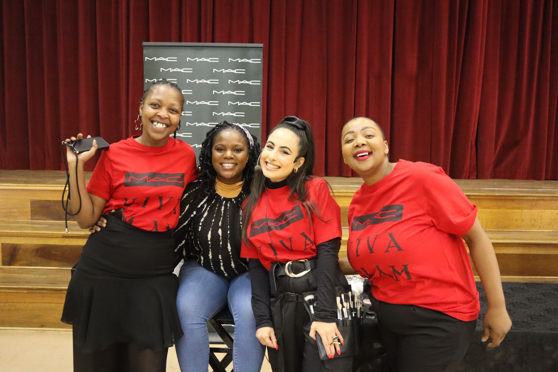 A group of young women are posing for a picture in front of a red curtain.