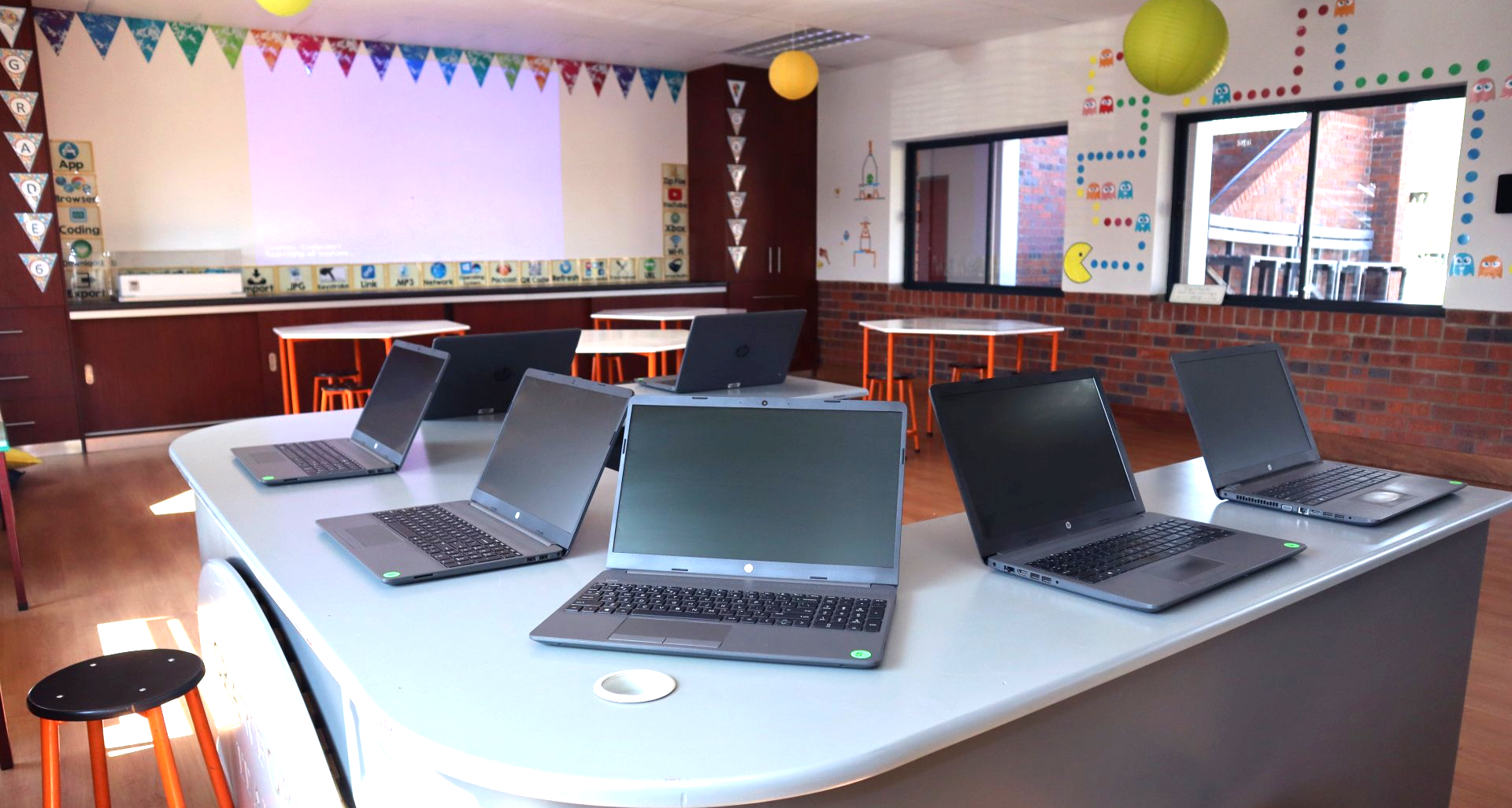 a group of laptops are sitting on a table in a classroom .