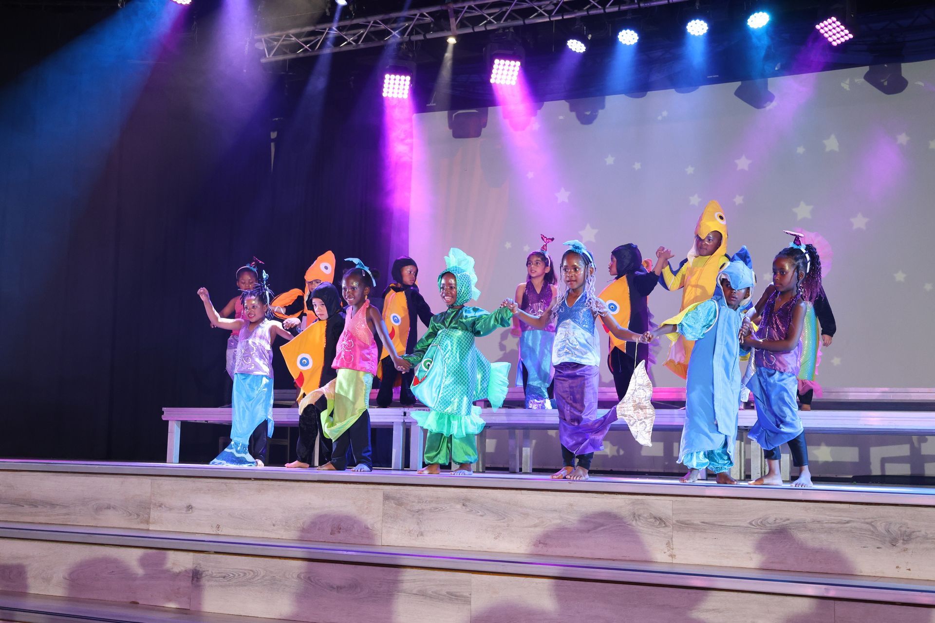 A group of children in costume are dancing on a stage