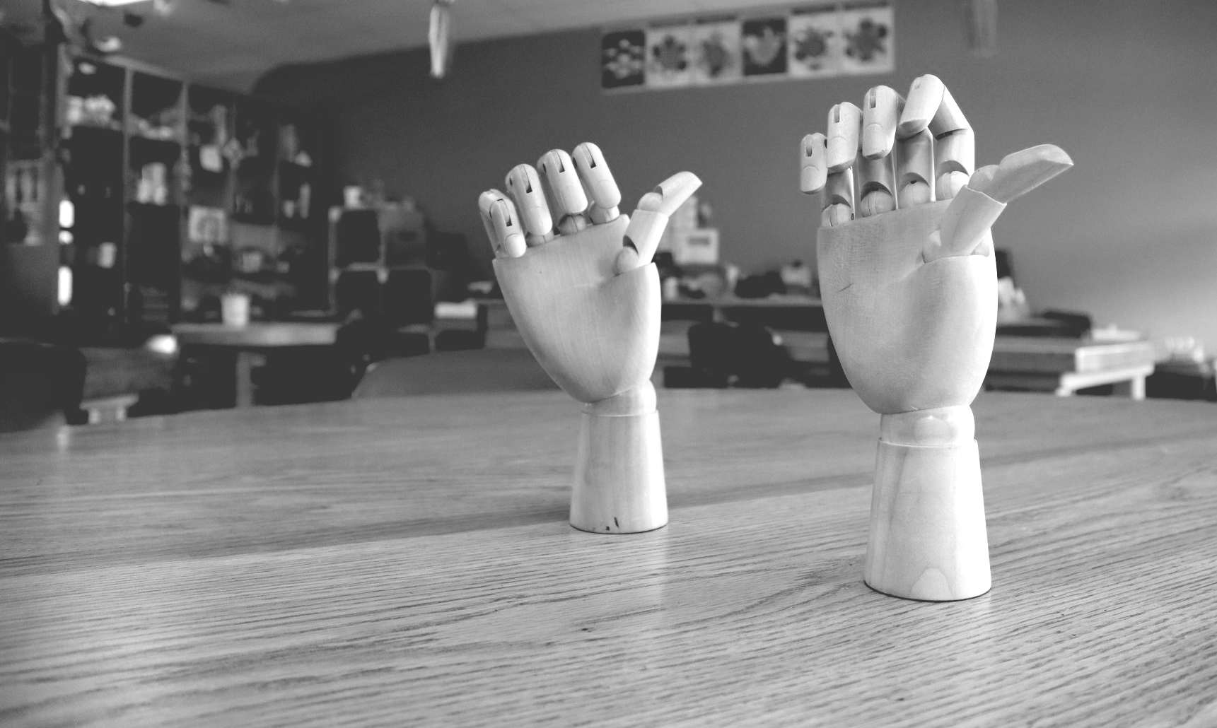 two mannequin hands are sitting on a wooden table in a black and white photo .