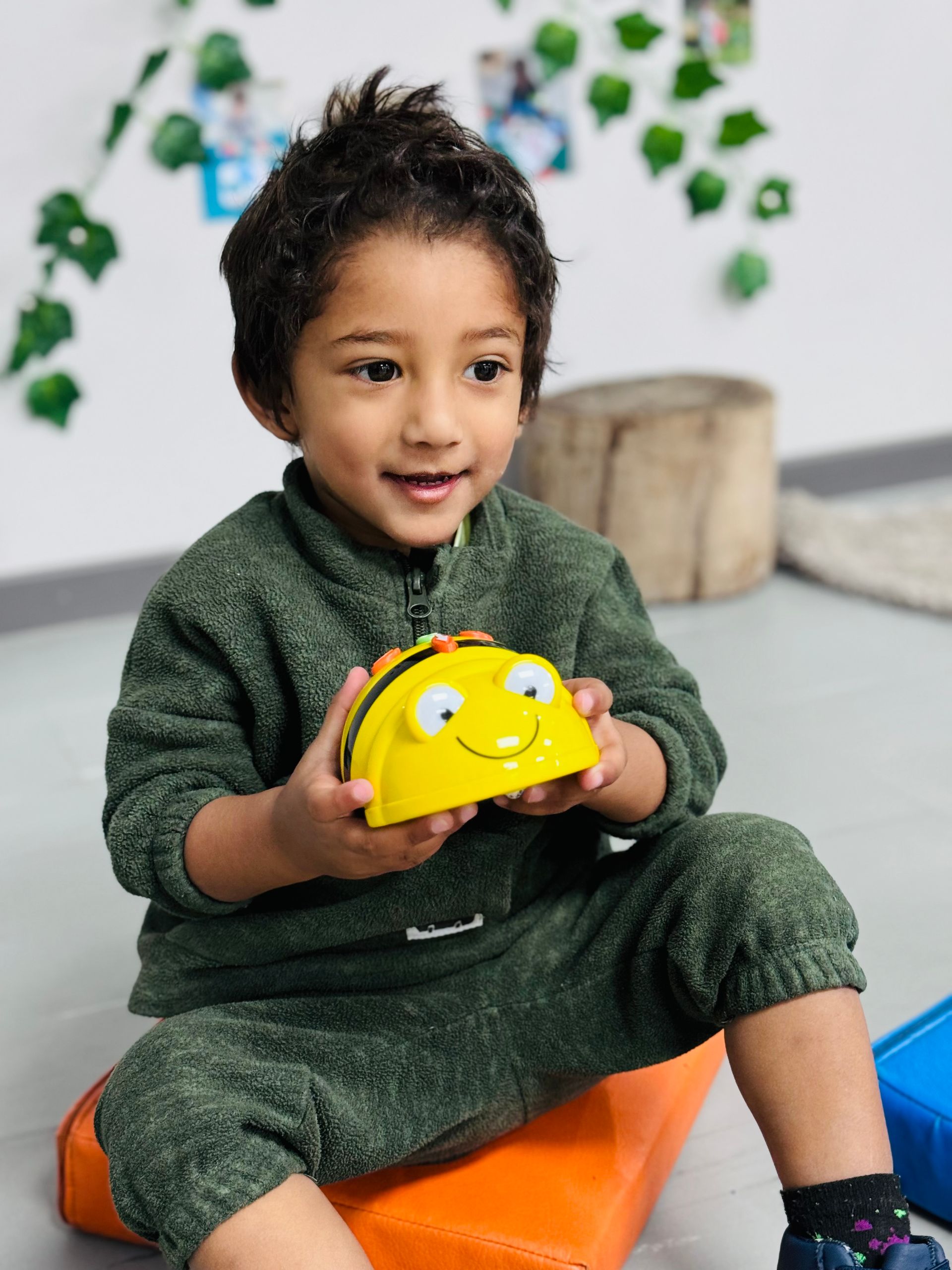 A young boy is holding a yellow toy with a face on it