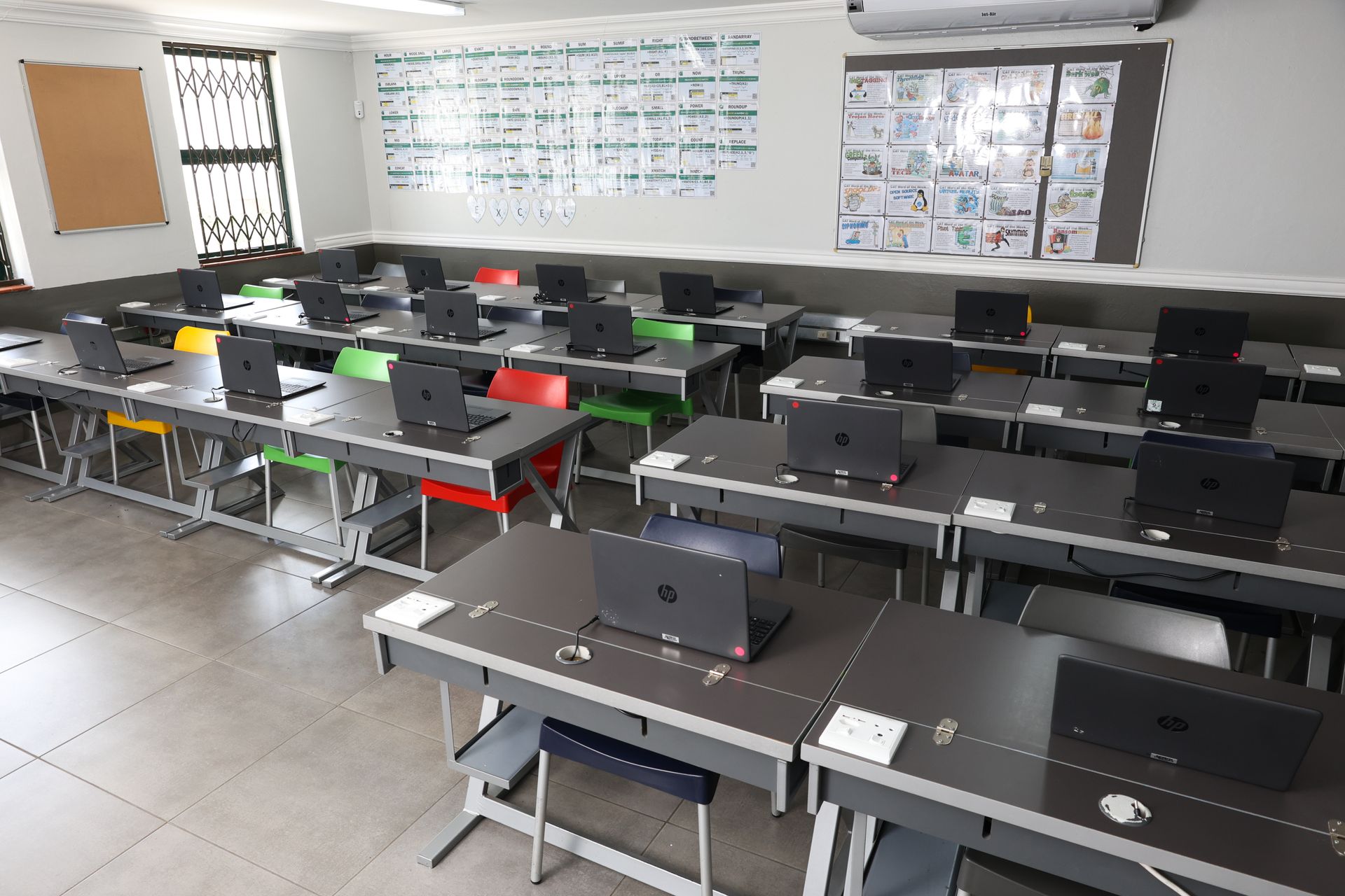 a row of laptops are sitting on a table and one of them says 12:10 on the screen