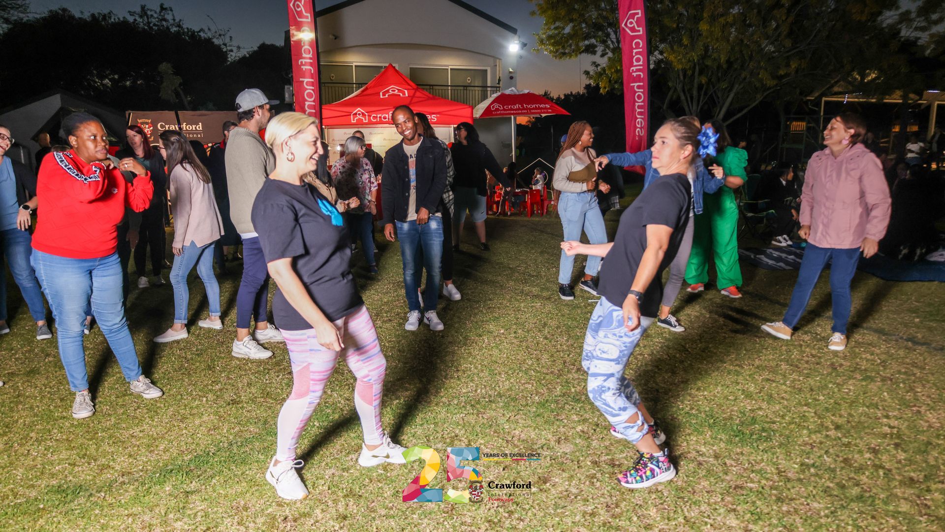 A group of people are dancing in a park at night.