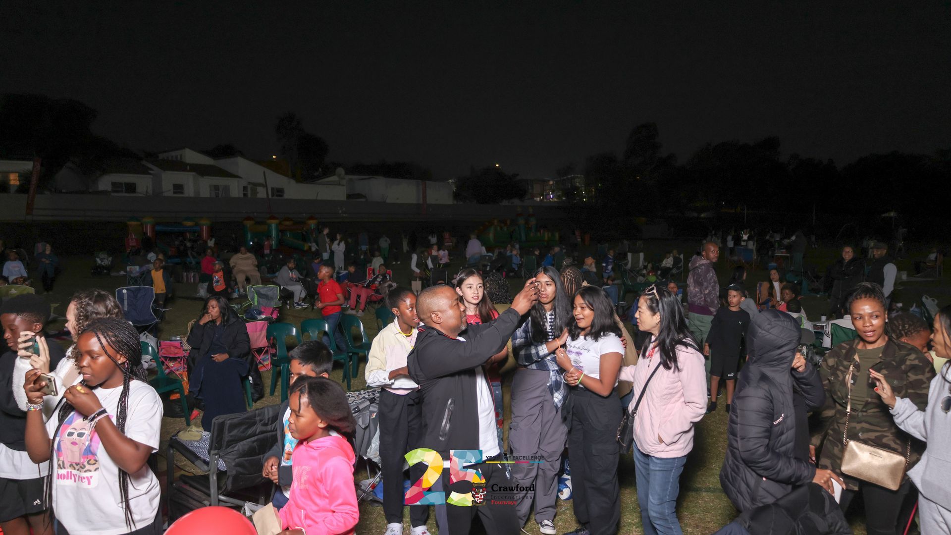 A large group of people are standing in a field at night.