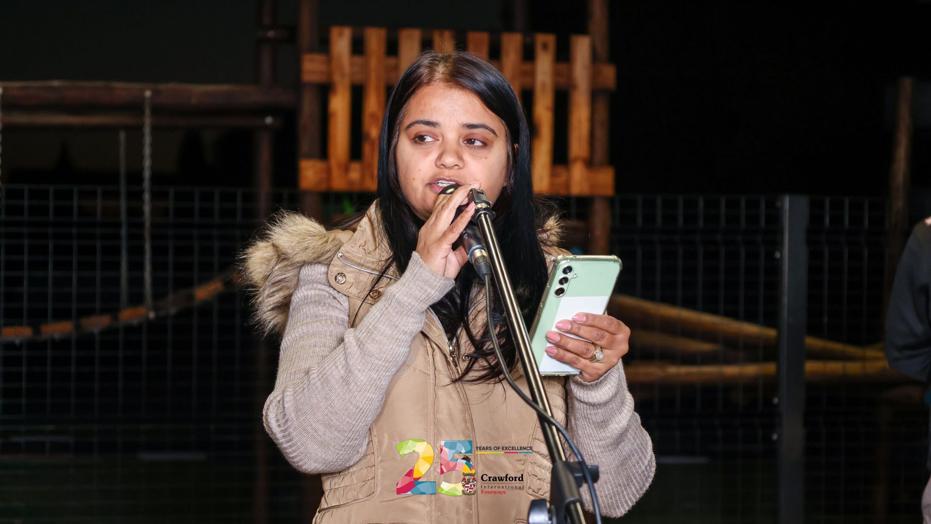 A woman is singing into a microphone while holding a cell phone.