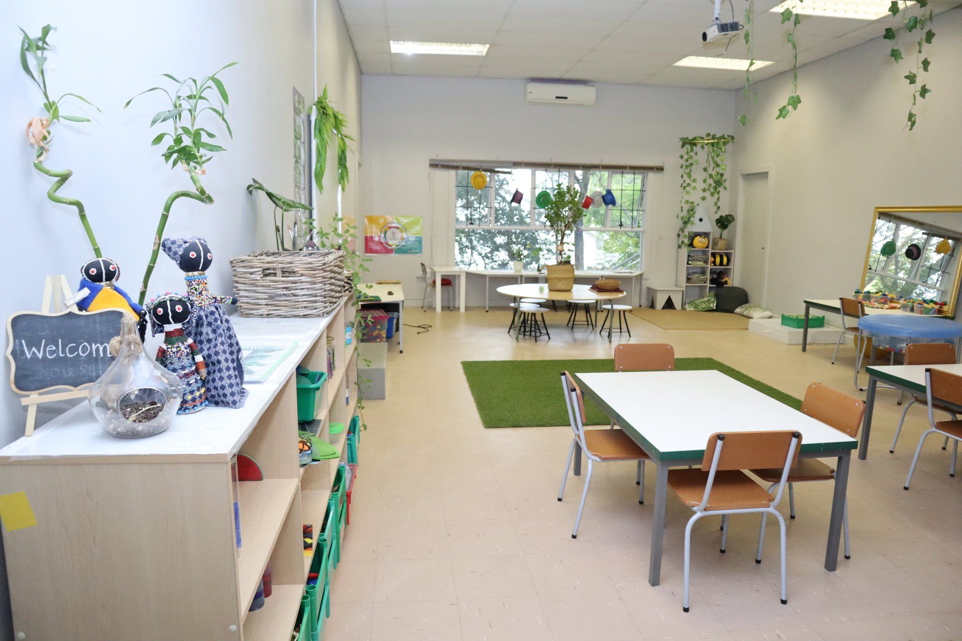 A classroom with tables and chairs and a sign that says welcome