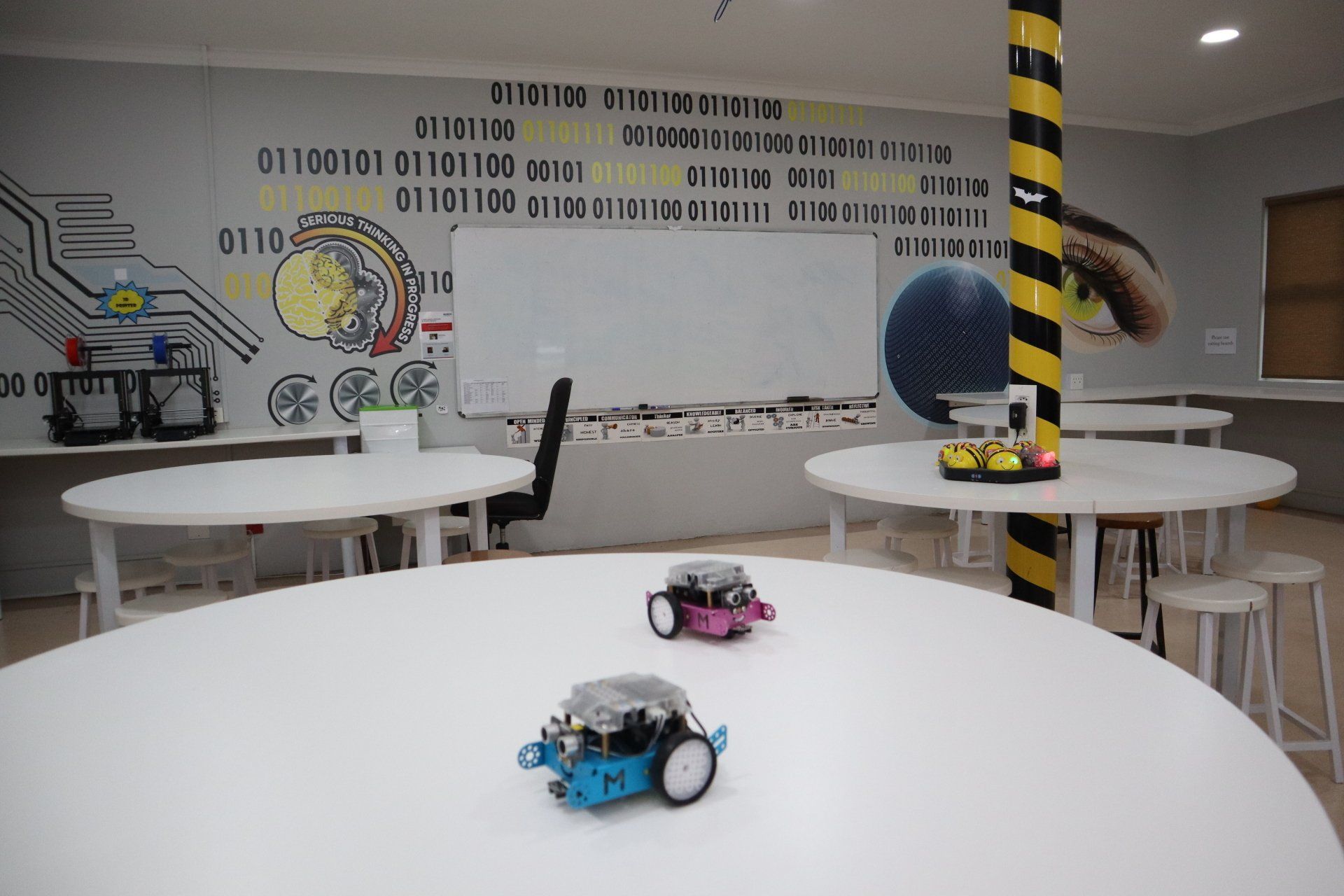 two robots are sitting on a white table in a room .