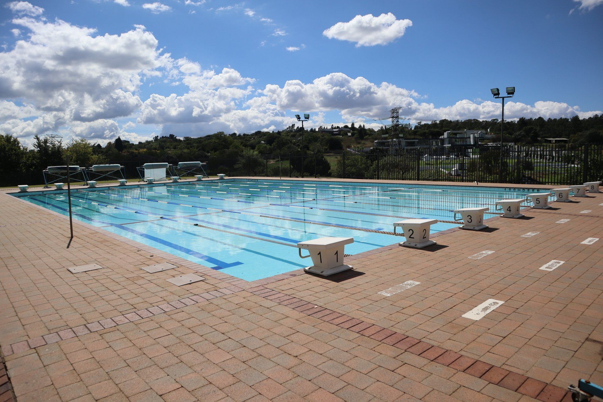 A large swimming pool surrounded by bricks on a sunny day