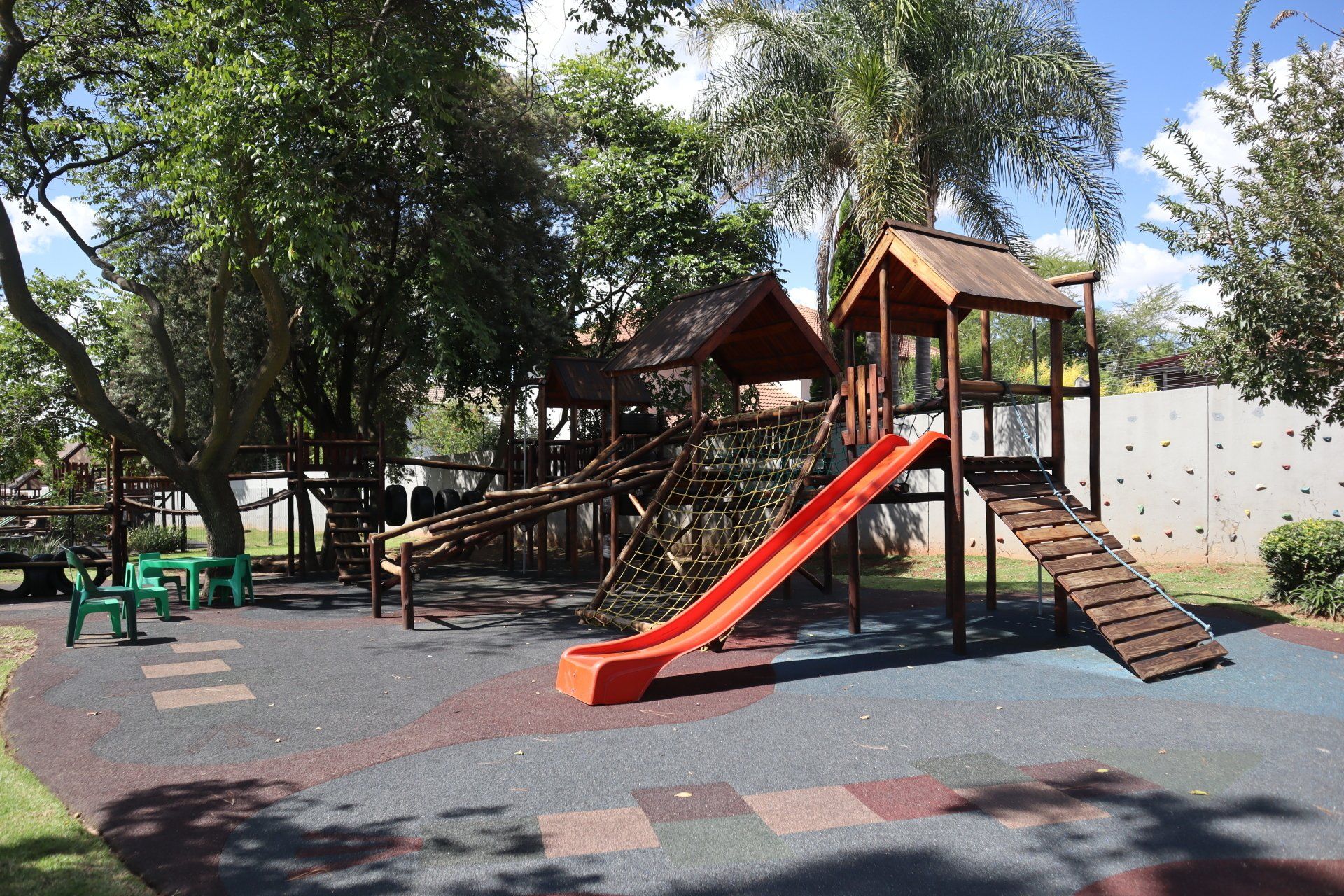 A playground with a red slide and a wooden house