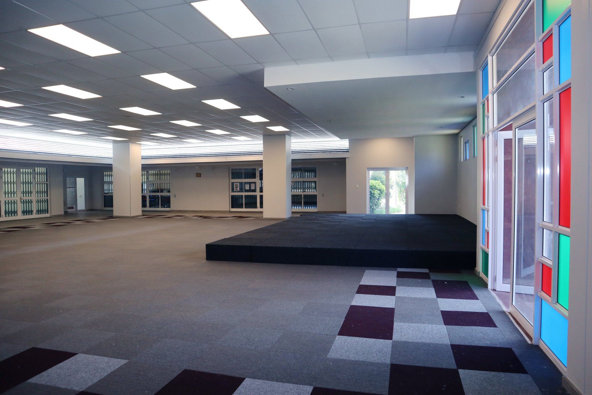 a large room with a stage and glass windows