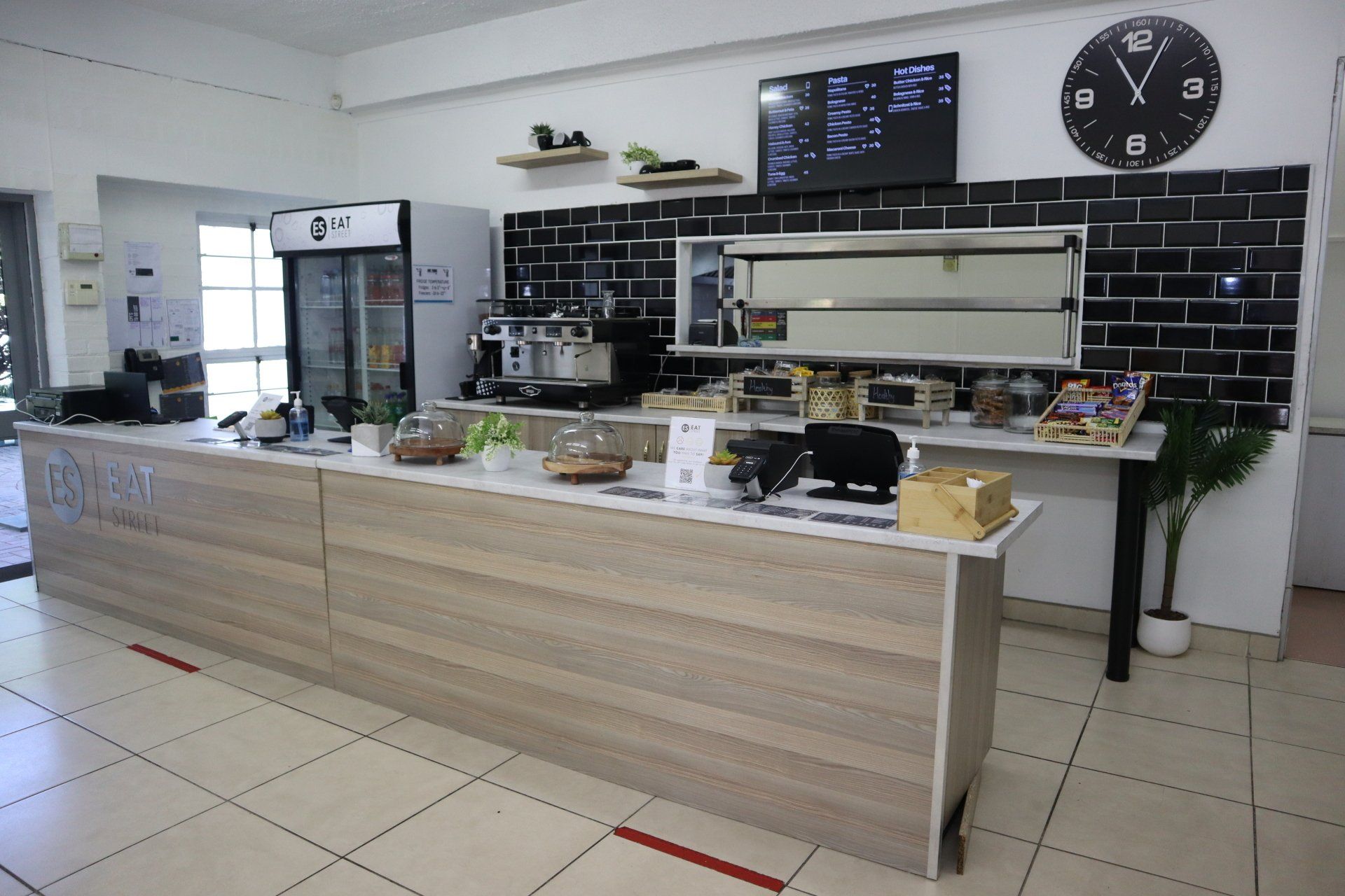 A restaurant with a long wooden counter and a clock on the wall.
