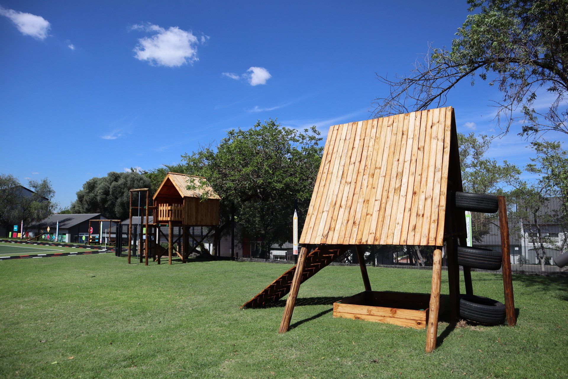 a wooden playground with a slide and a sandbox in a park .