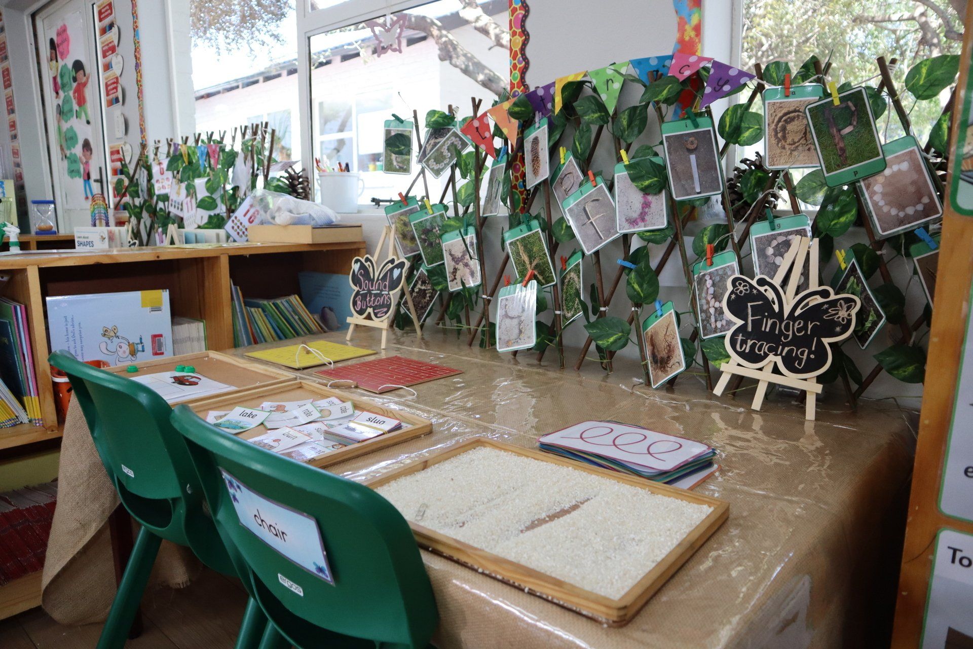 a table in a classroom with green chairs and a table cloth .