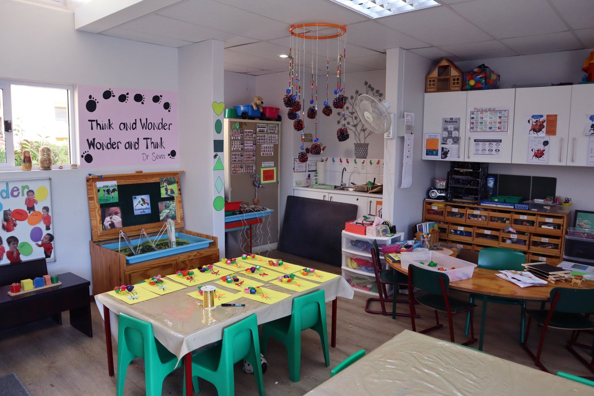 a classroom with tables and chairs and a sign on the wall