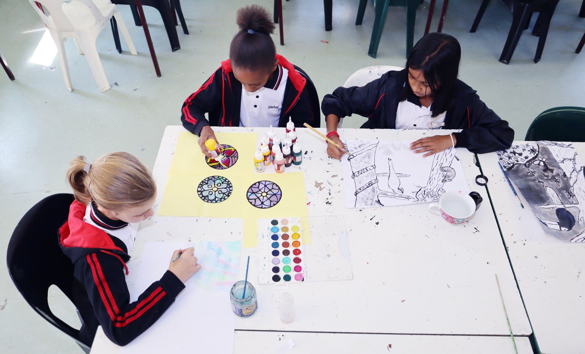 a group of children are sitting at a table painting