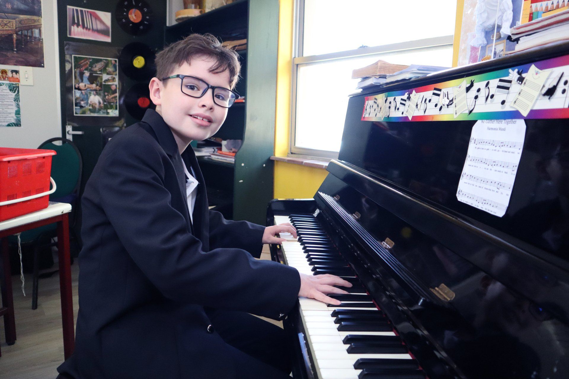 a young boy is playing a piano in a classroom .