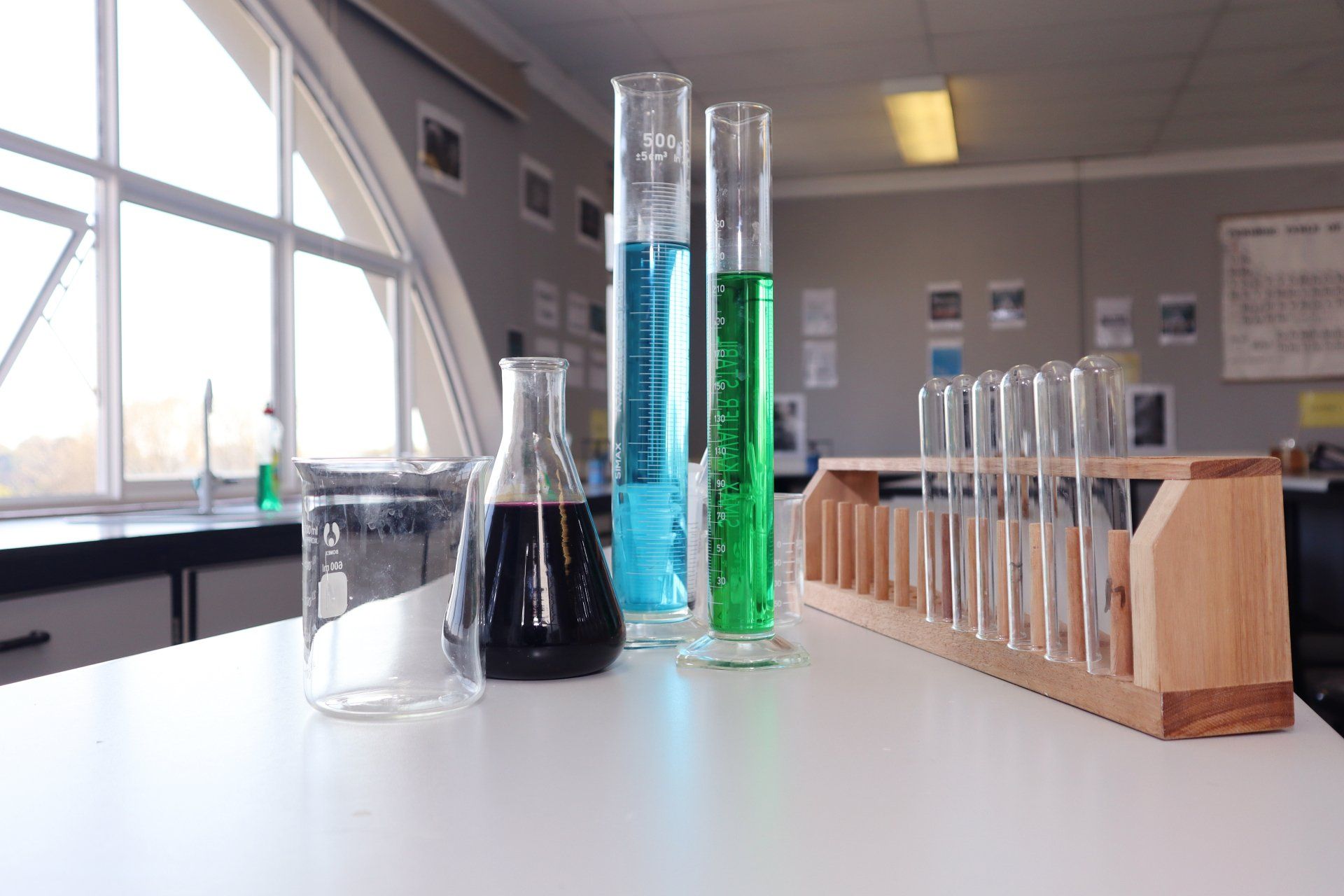 a row of test tubes and beakers on a table in a classroom .