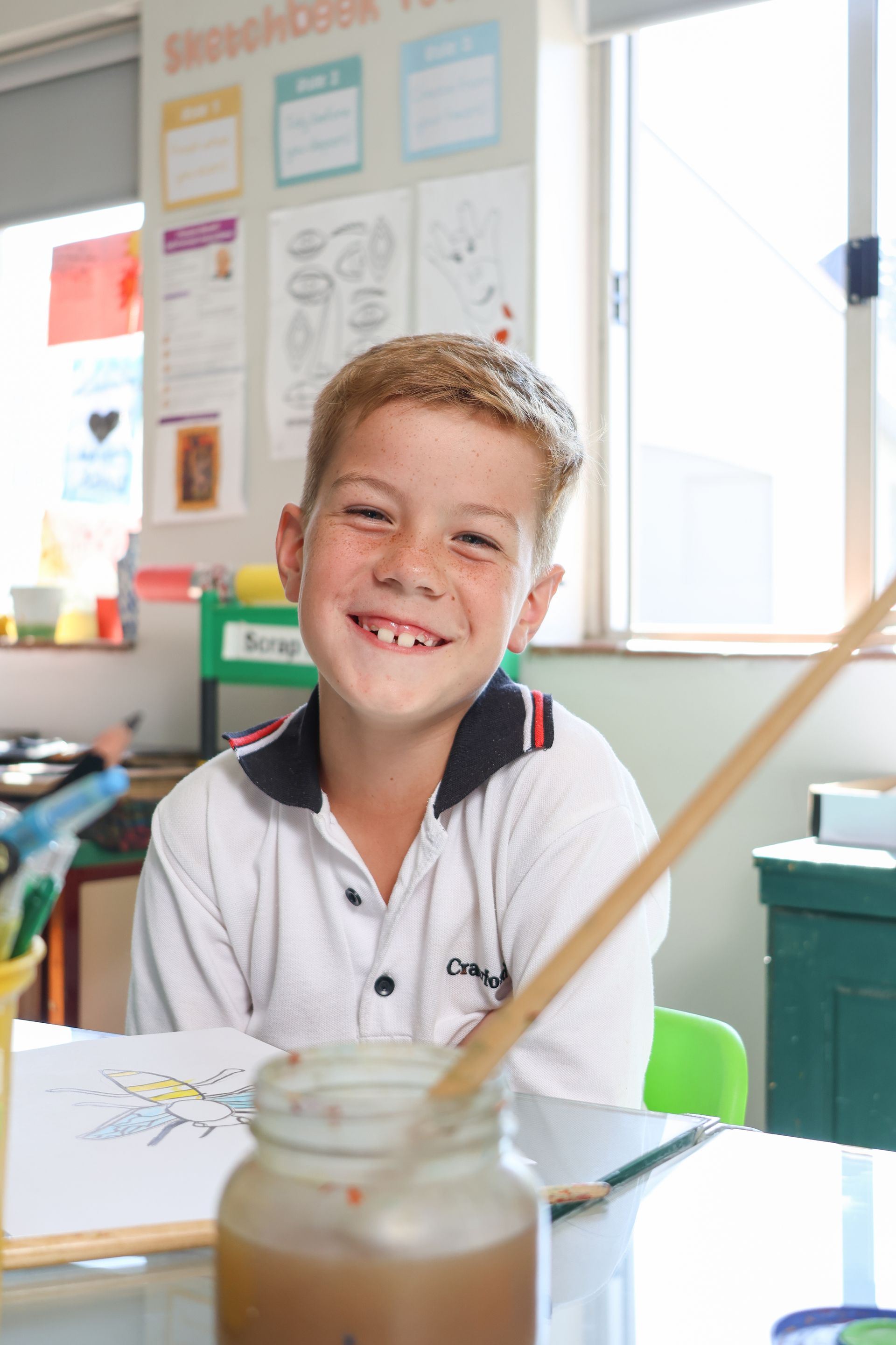 a group of children are sitting at a table painting