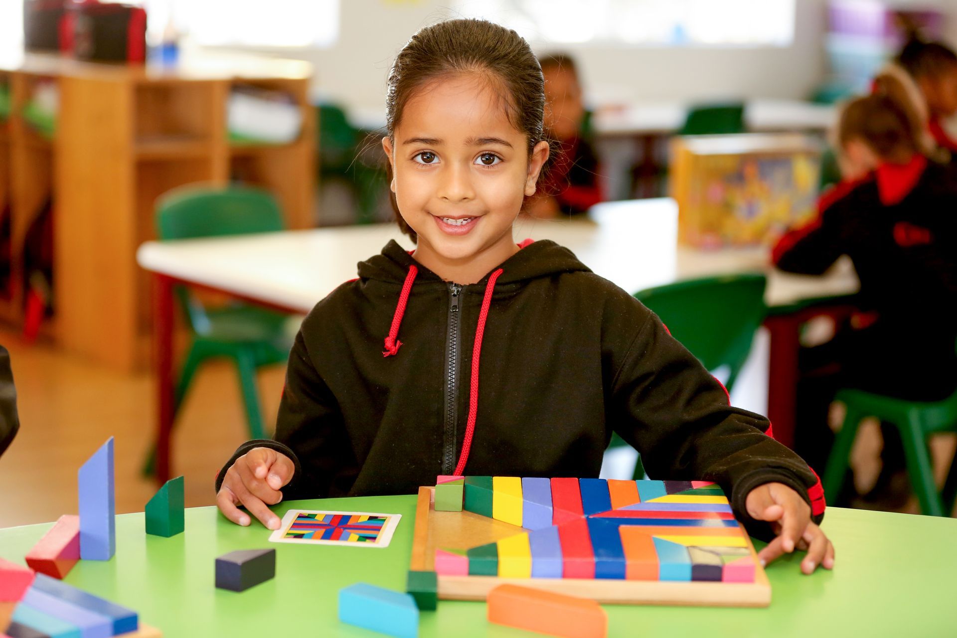 a young boy in a red shirt is sitting at a desk in front of a computer .