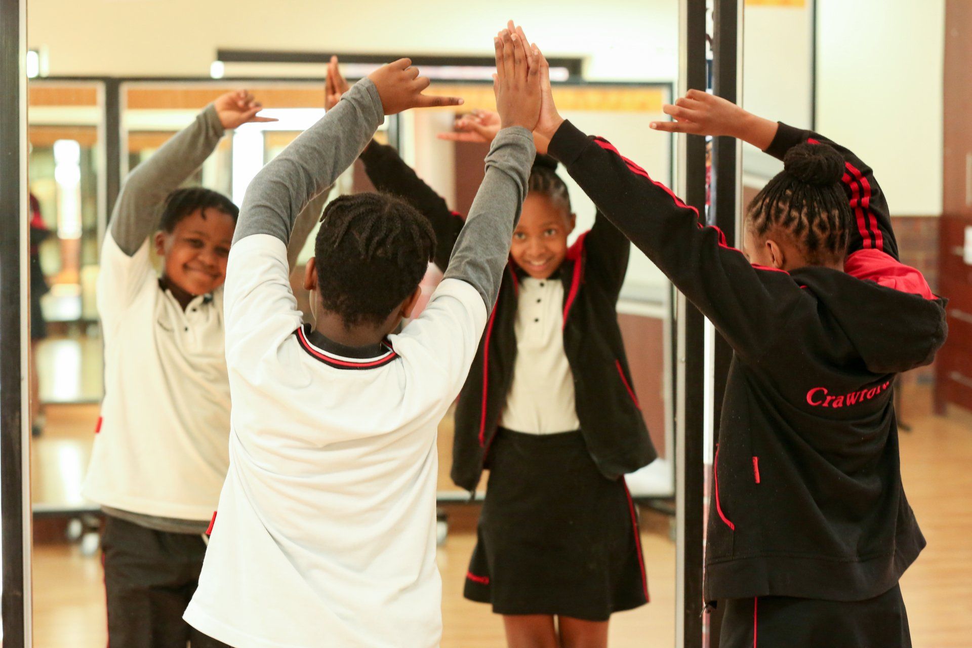 a group of children are giving each other a high five in front of a mirror .