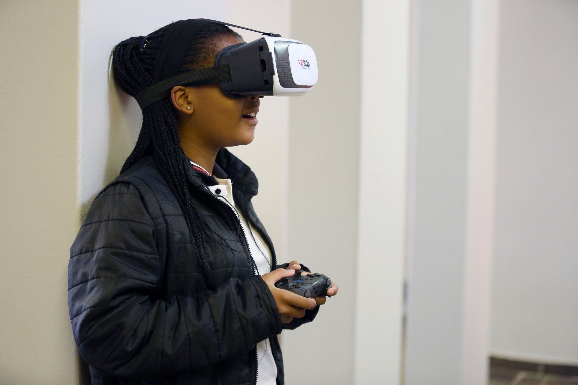 a woman is wearing a virtual reality headset and holding a remote control .