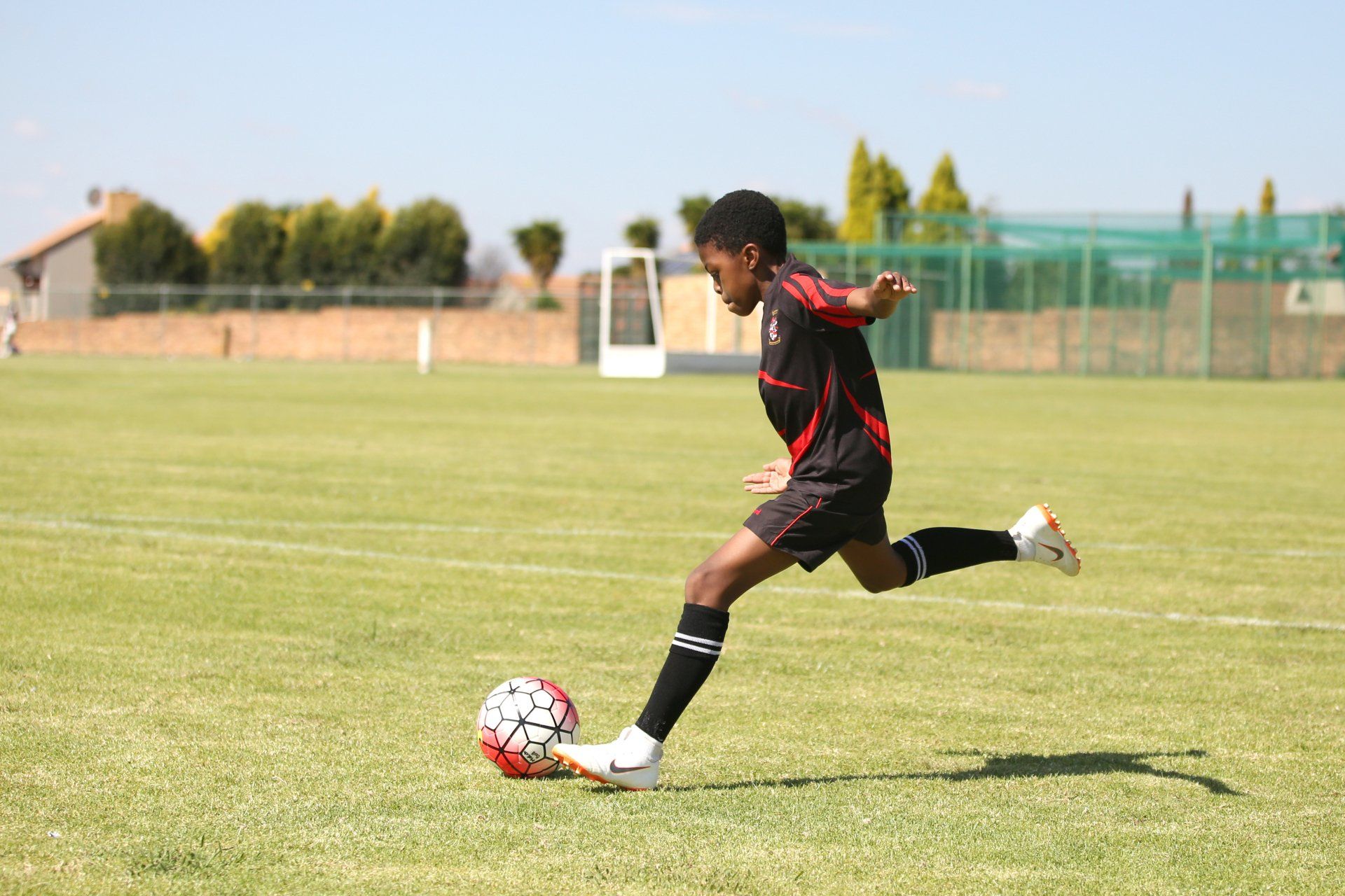 a young boy is kicking a soccer ball on a field .