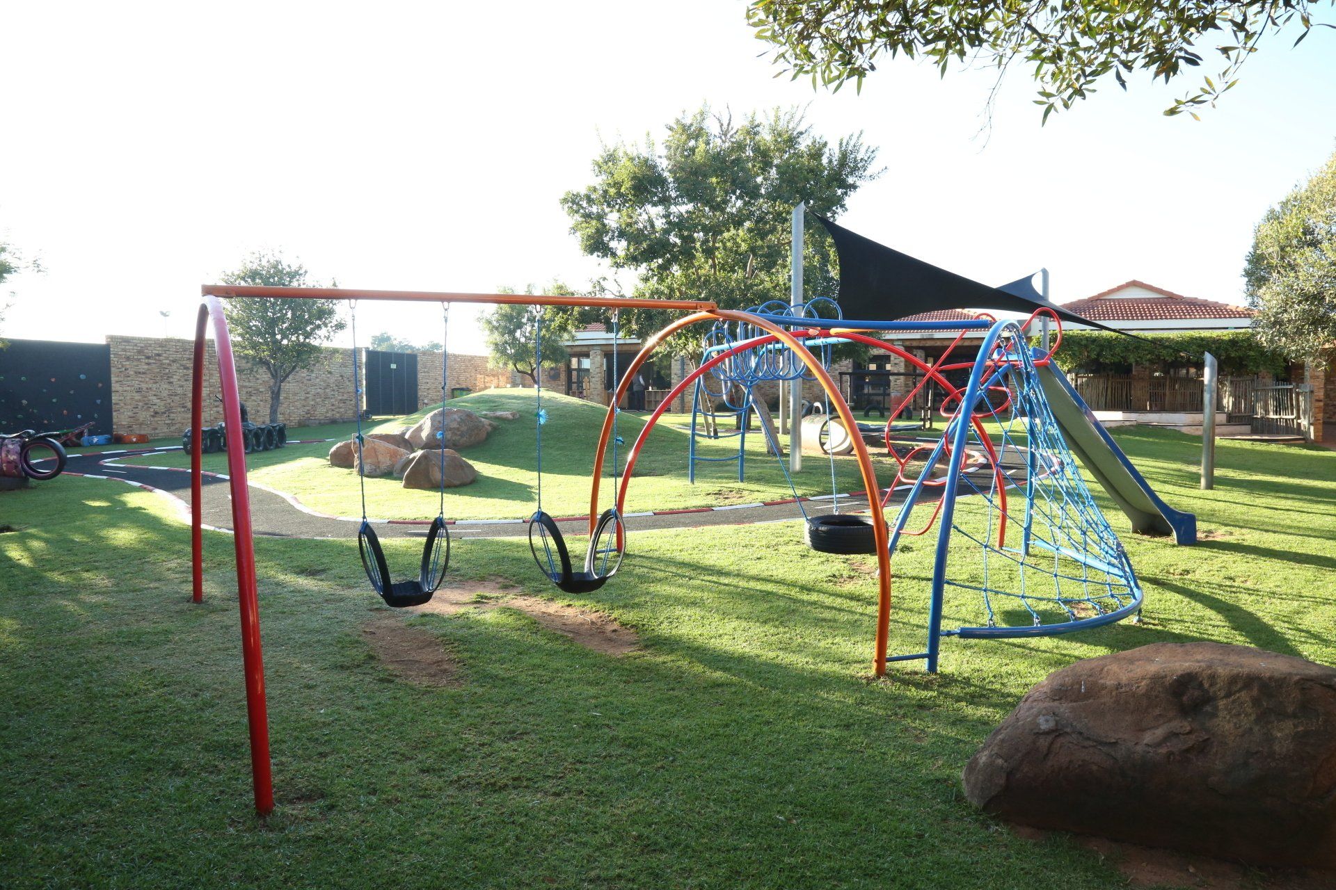 A playground with swings and a slide in a grassy area.