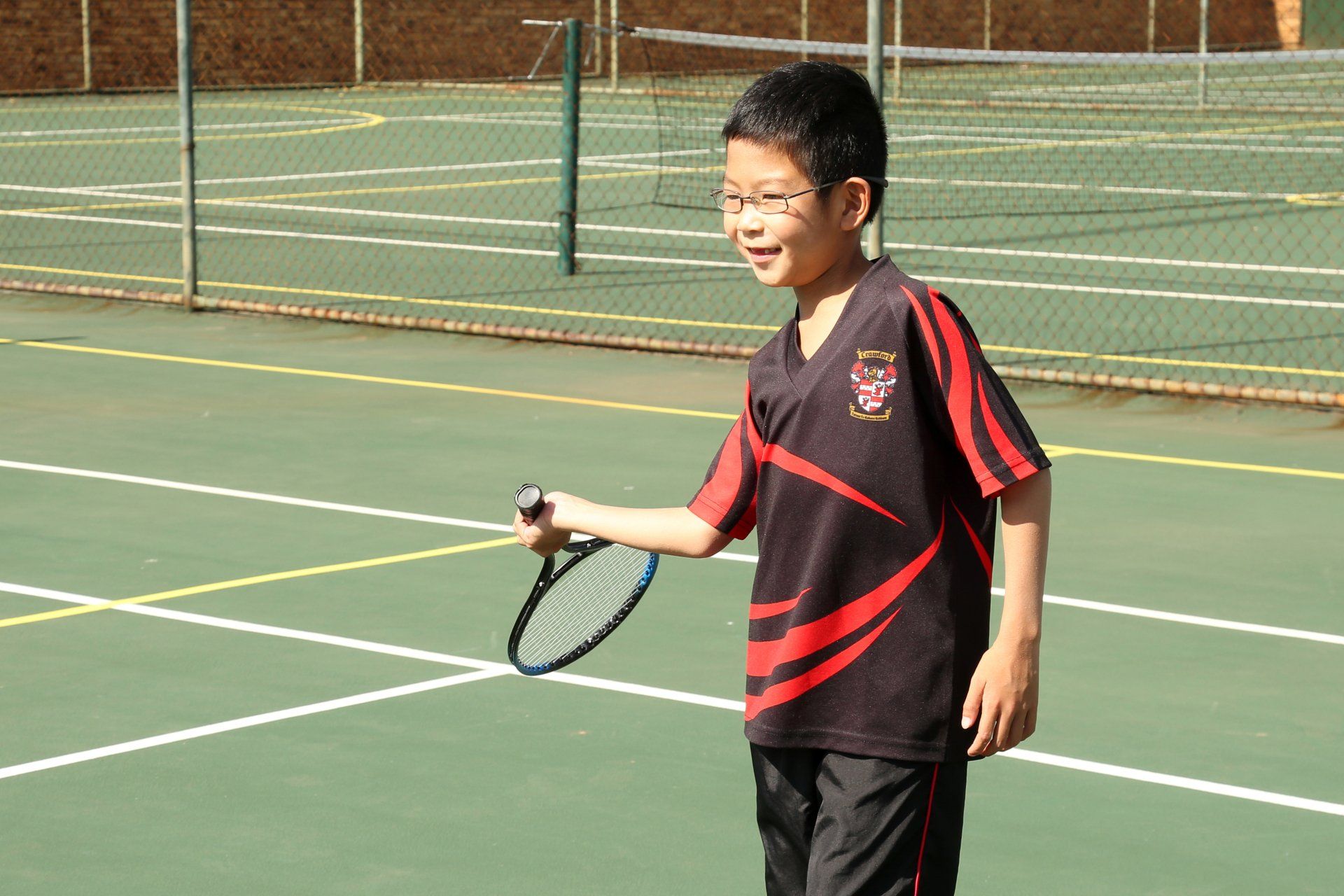 A young boy is holding a tennis racquet on a tennis court
