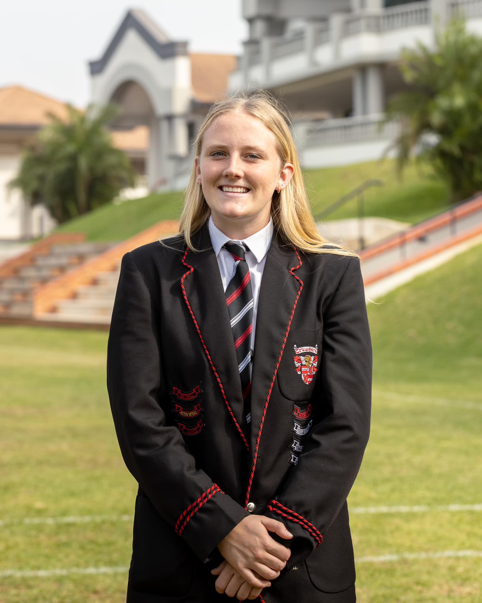 A girl in a school uniform is standing in front of a building.