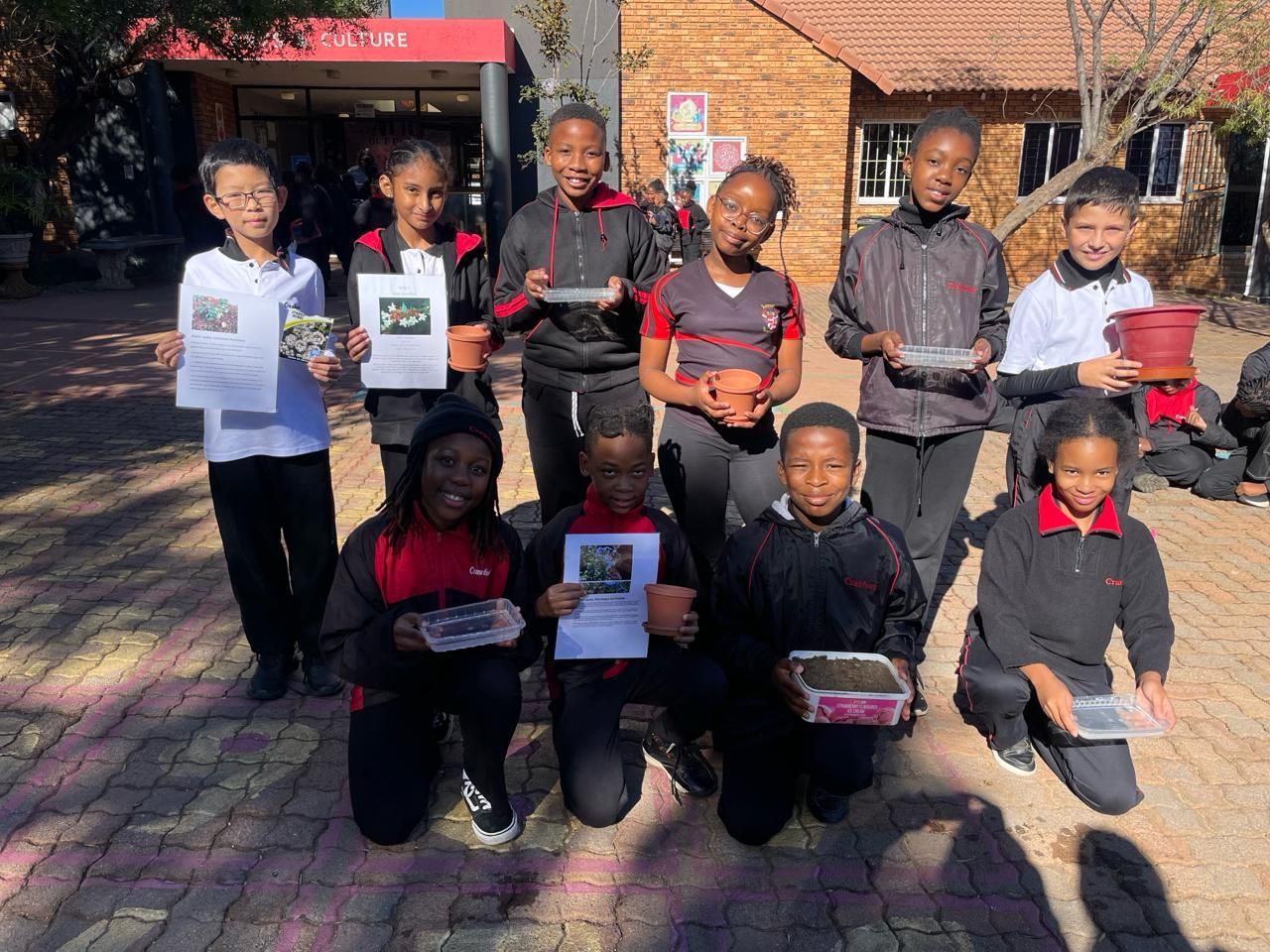 A group of children are posing for a picture in front of a building.