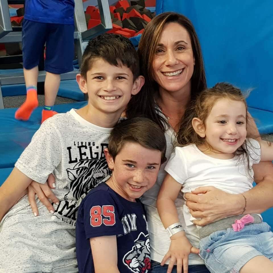 A woman is sitting on a bench with three children.