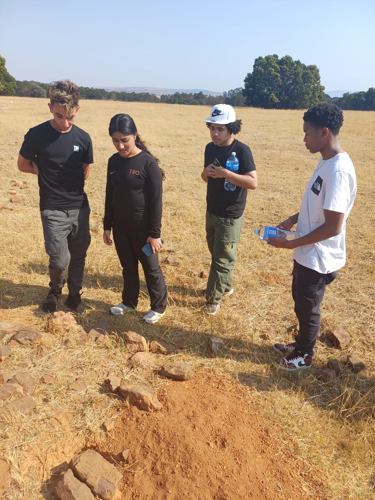 A group of people are standing in a field looking at something.