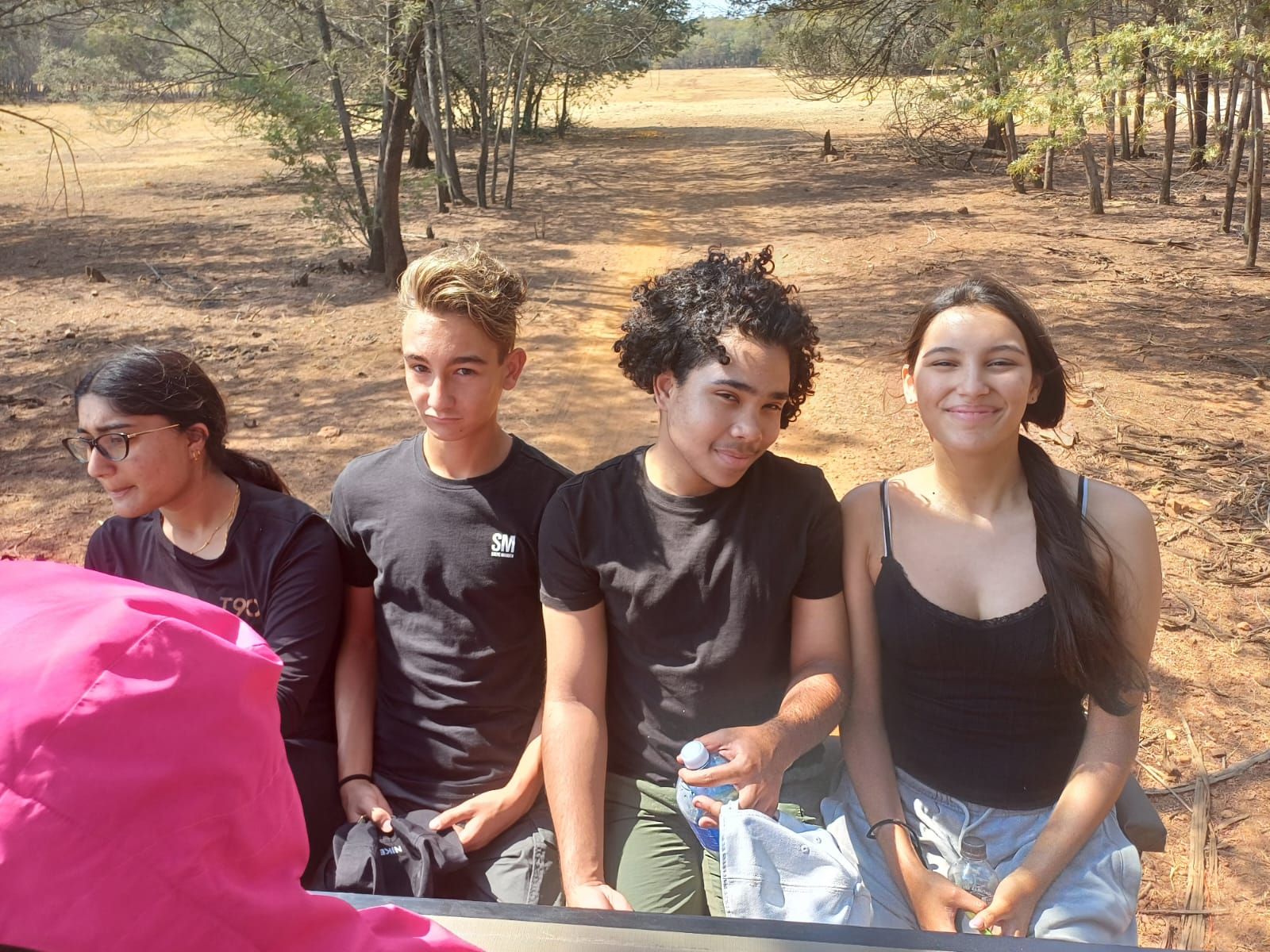 A group of young people are sitting in the back of a truck.