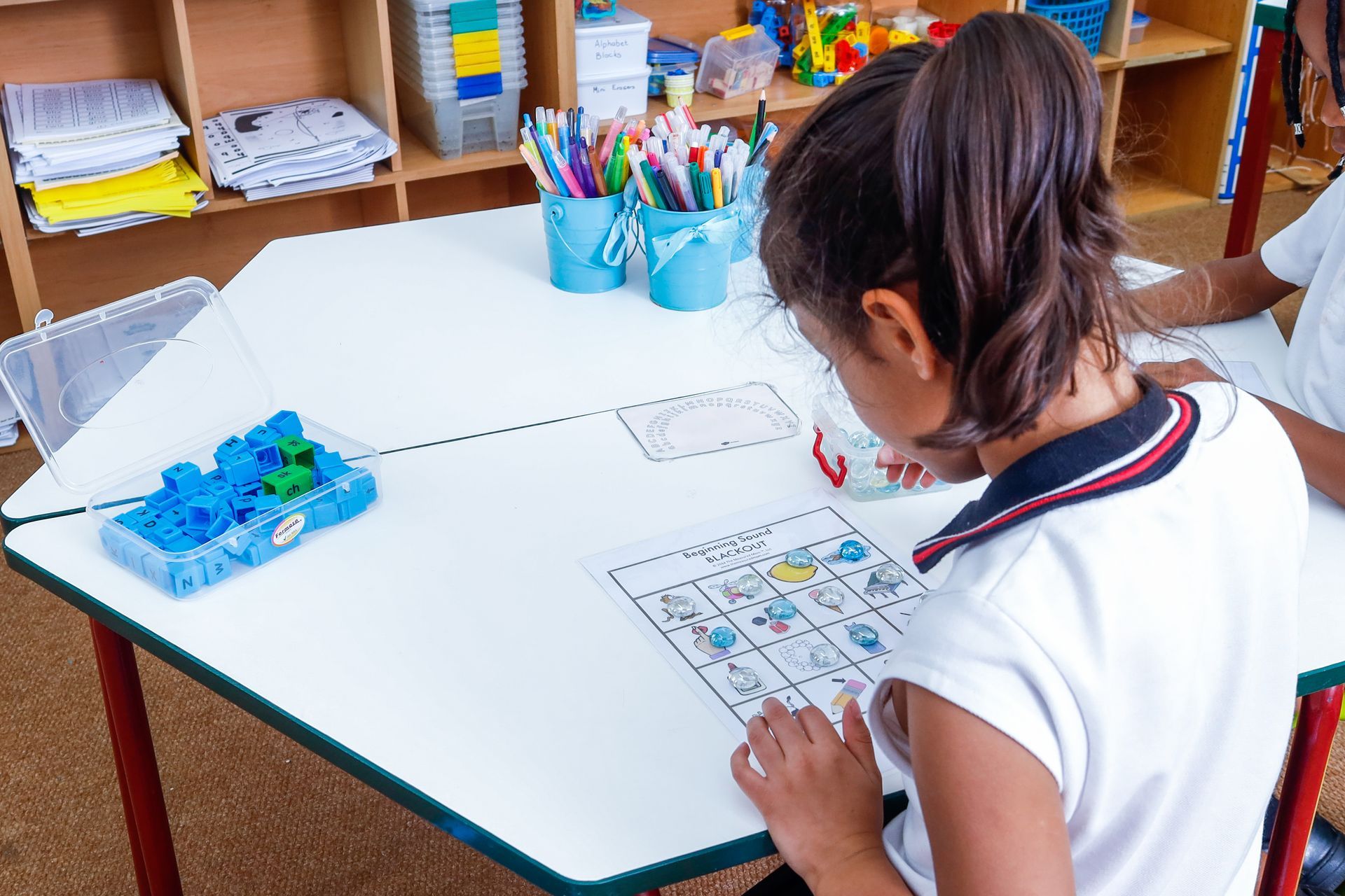 a little girl is sitting at a table with a puzzle on it .