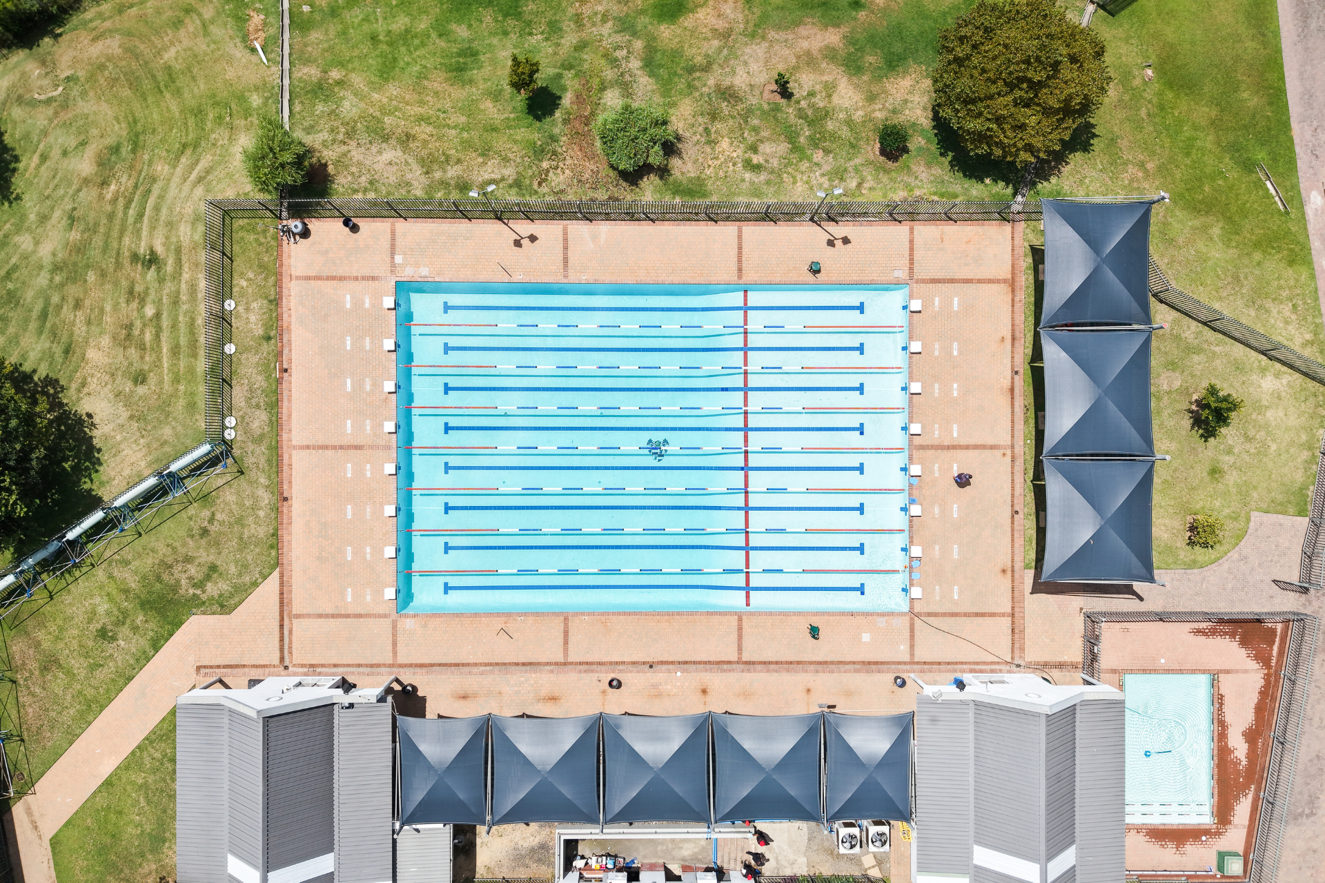 A large swimming pool surrounded by bricks on a sunny day