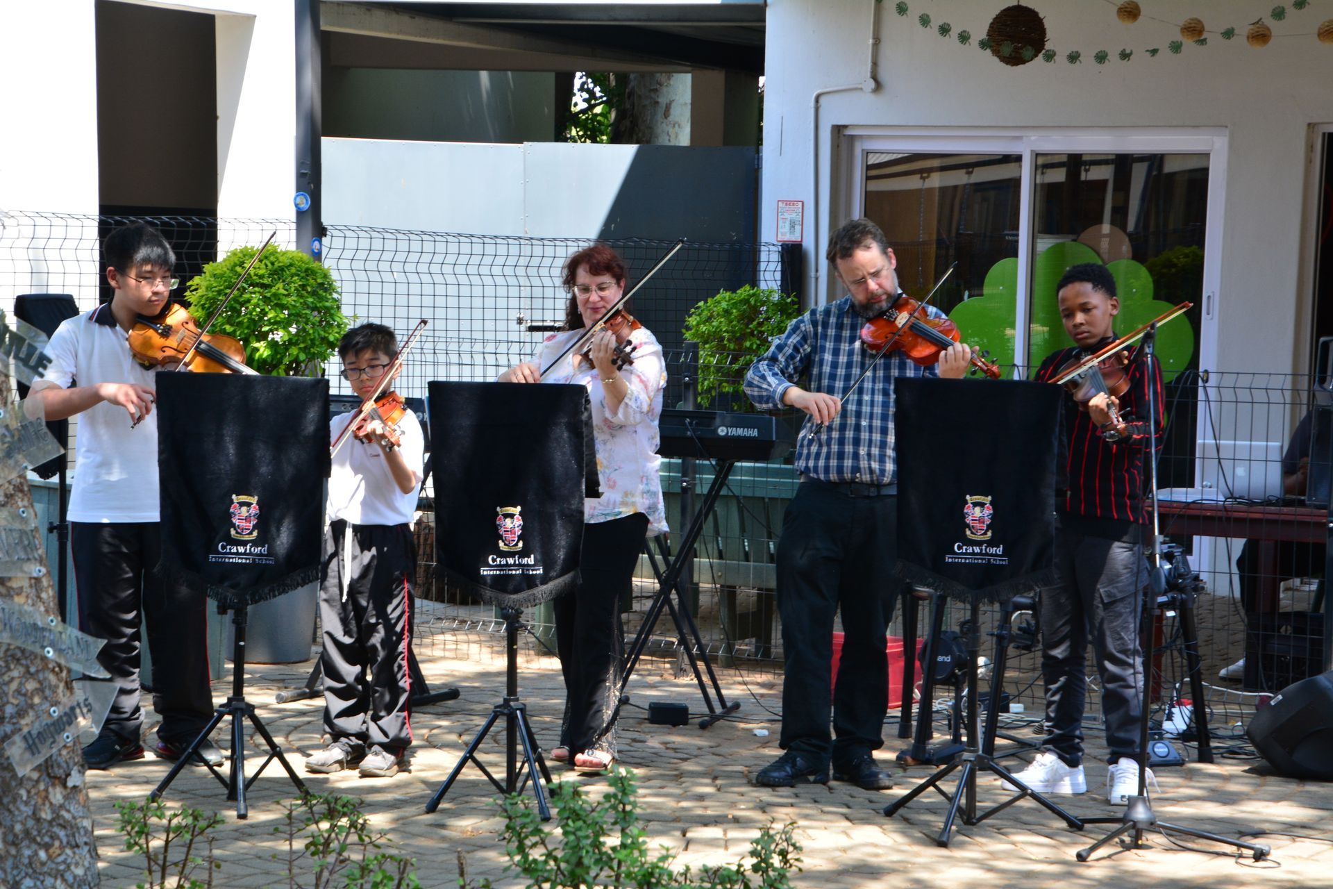 A group of people are playing violins in front of a building.