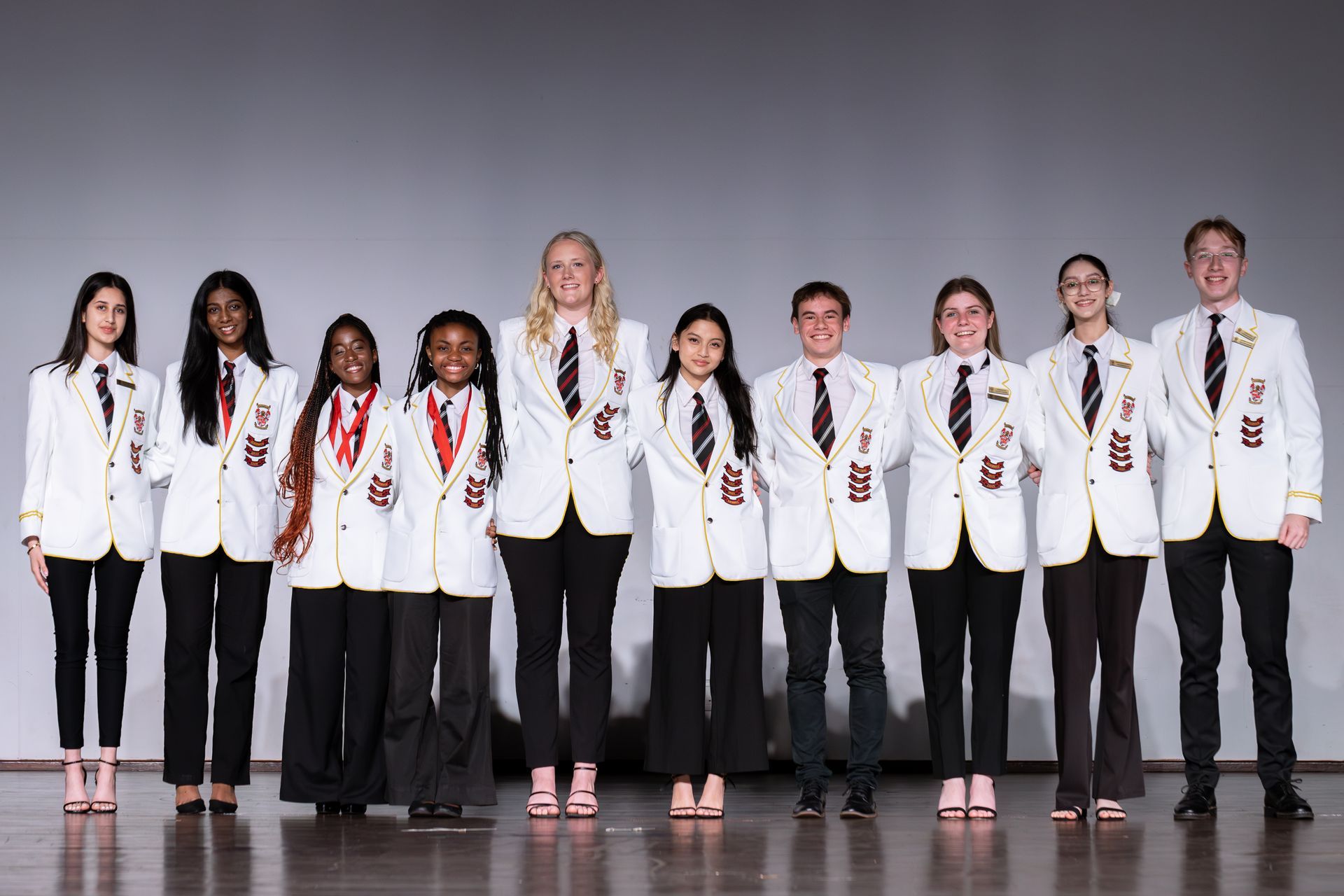 A group of people in white suits and black pants are standing next to each other on a stage.