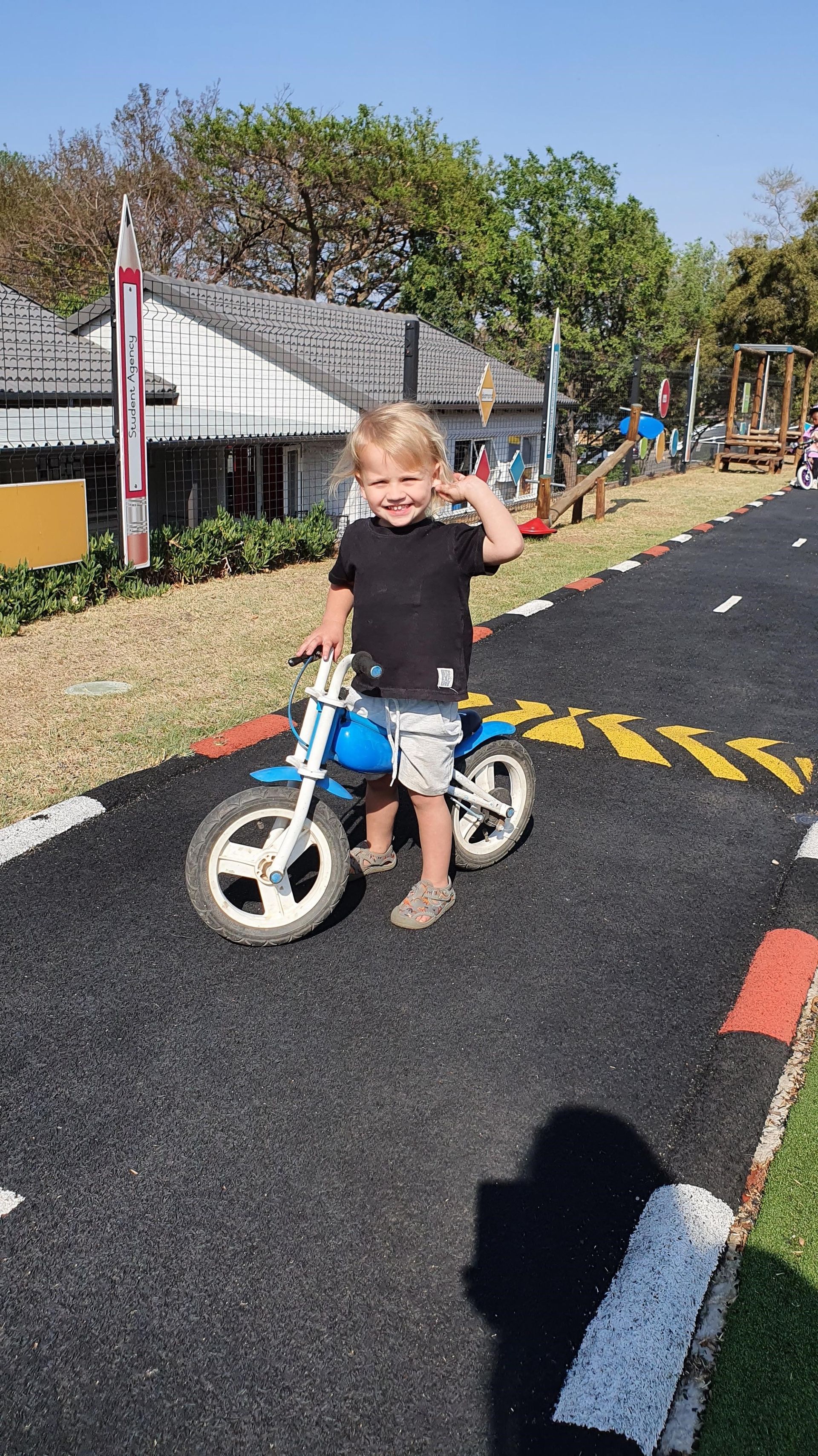 A young boy is riding a blue motorcycle on a road.