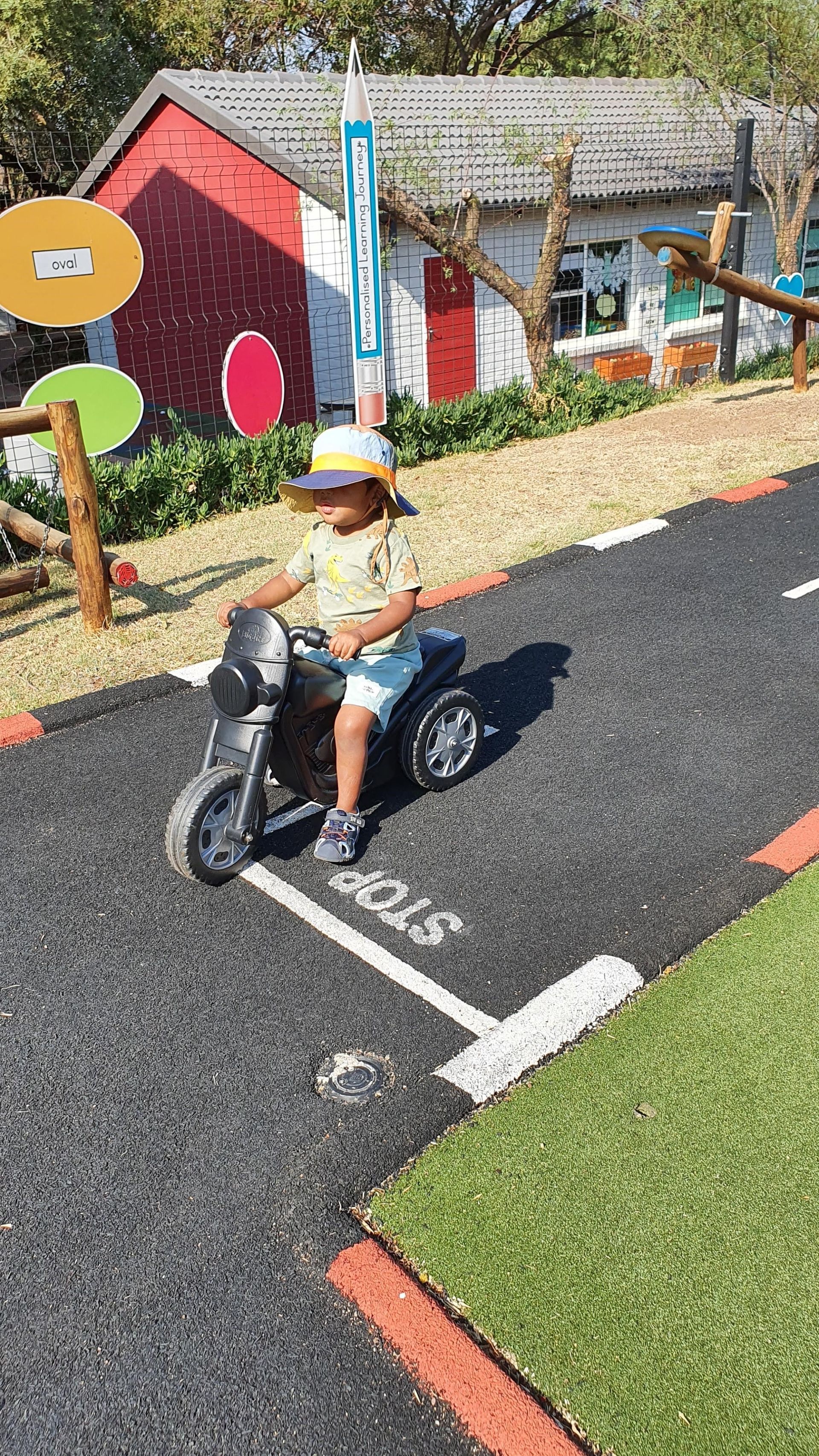 A young boy is riding a toy motorcycle on a road.
