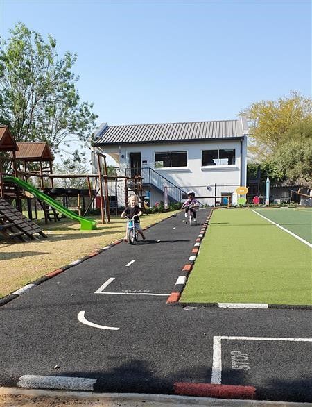Two children are riding bikes on a road in front of a house