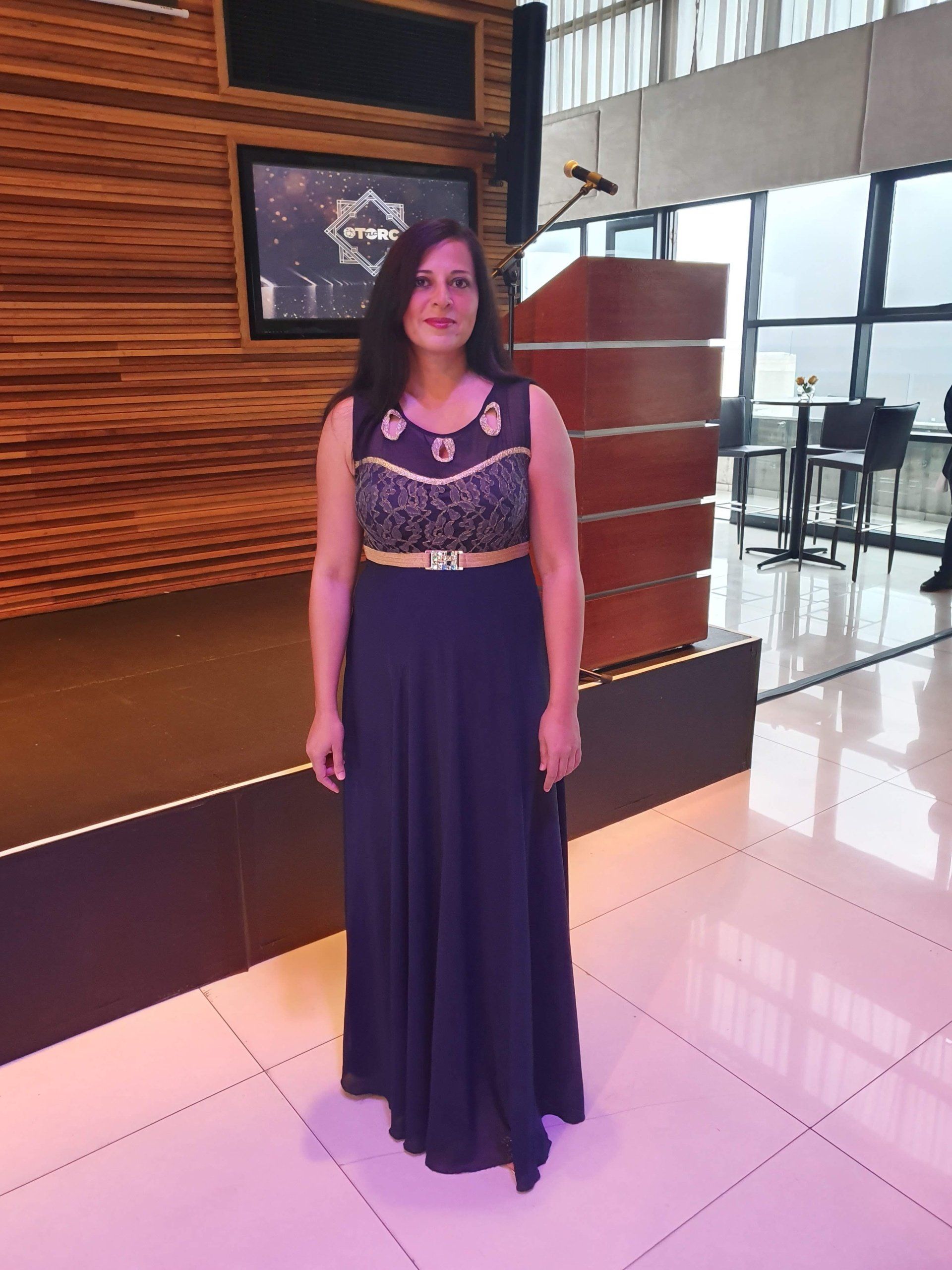 A woman in a long purple dress is standing in a room.