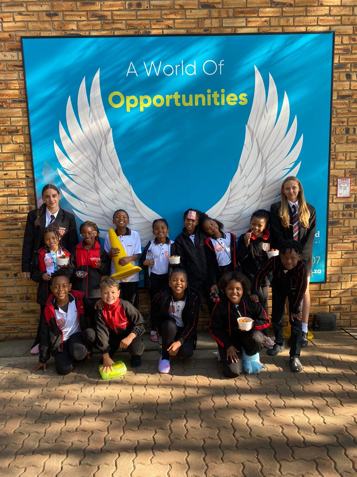 A group of children are posing for a picture in front of a sign that says `` a world of opportunities ''.