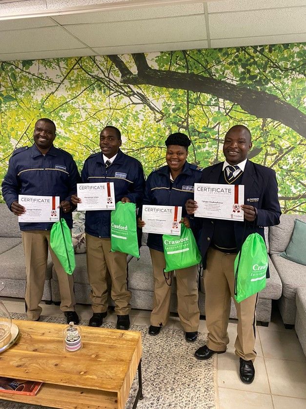 A group of people are standing next to each other in a living room holding certificates.