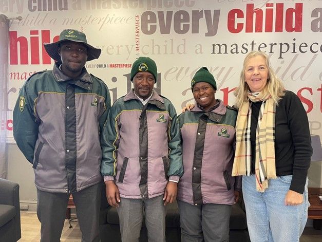 A group of people standing in front of a wall that says every child a masterpiece